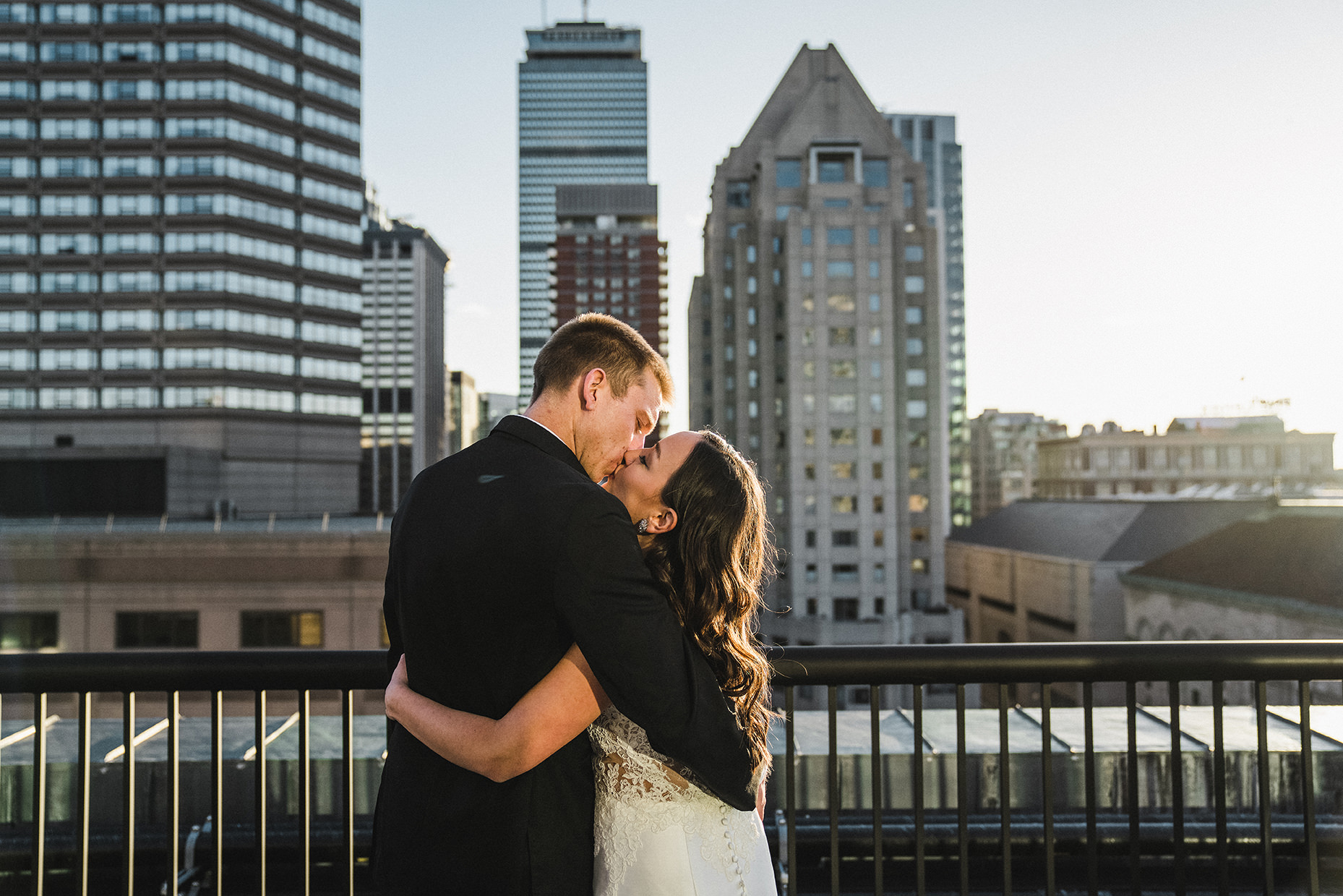 A candid portrait of a bride and groom kissing on the roof of fairmont copley during their boston wedding