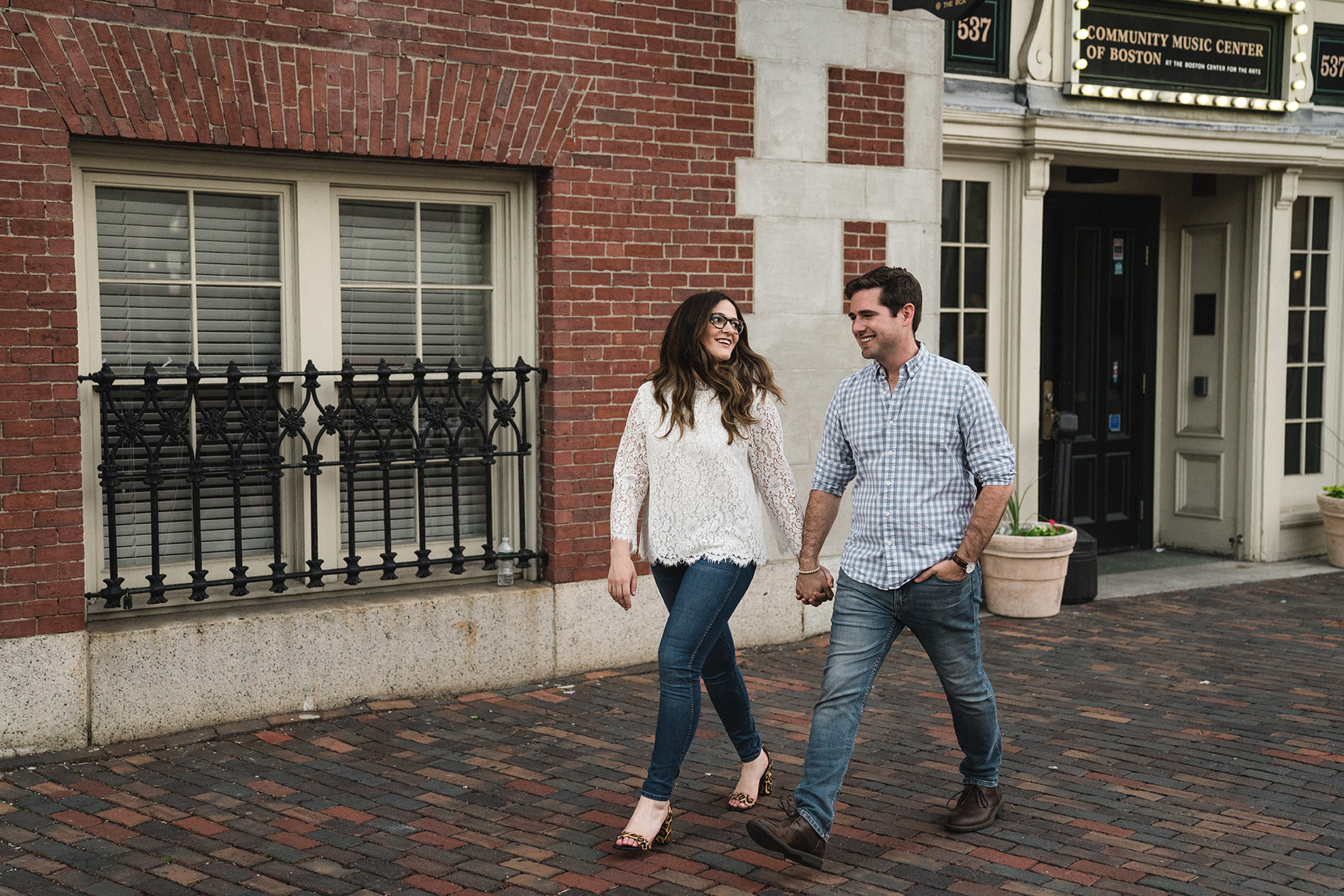 A documentary photograph of a couple walking outside Cyclorama in the South End during their Boston Engagement Session