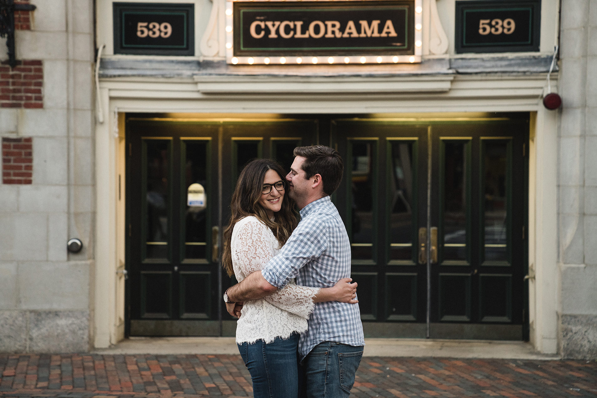 A documentary photograph of a couple hugging outside cyclorama during their South End Engagement Session