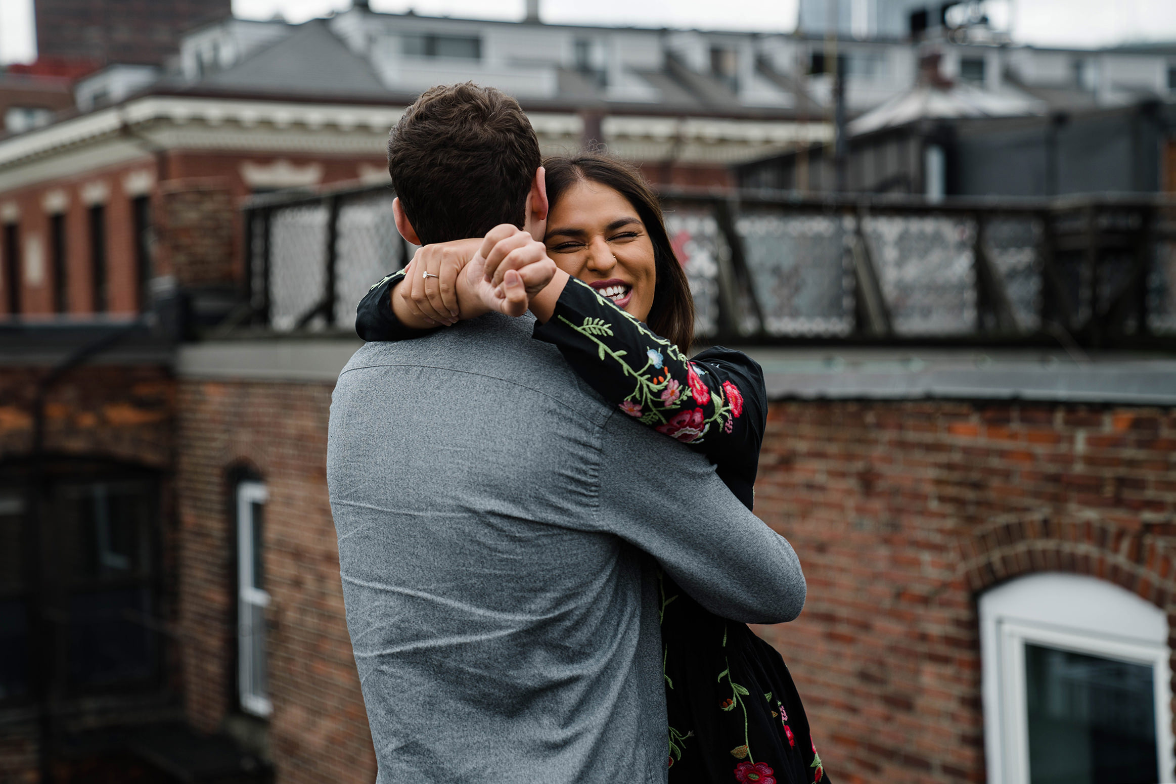 A documentary photograph of a couple hugging and laughing during their in home beacon hill engagement session in boston