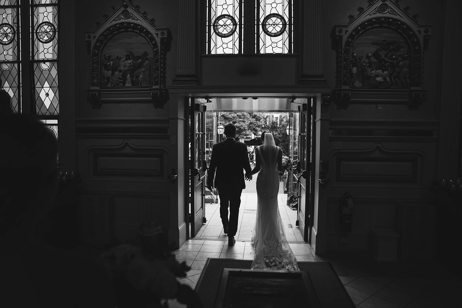 A documentary photograph of a couple walking out of a church together, just married, after their Boston wedding ceremony