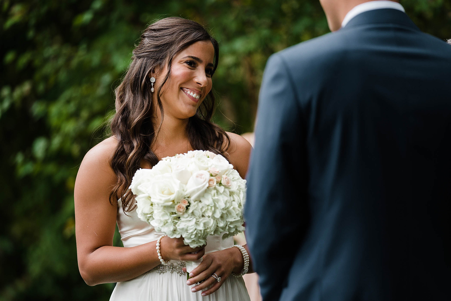 A documentary photograph of a bride smiling during her outdoor wedding ceremony at the Inn at Hastings Park outside of Boston