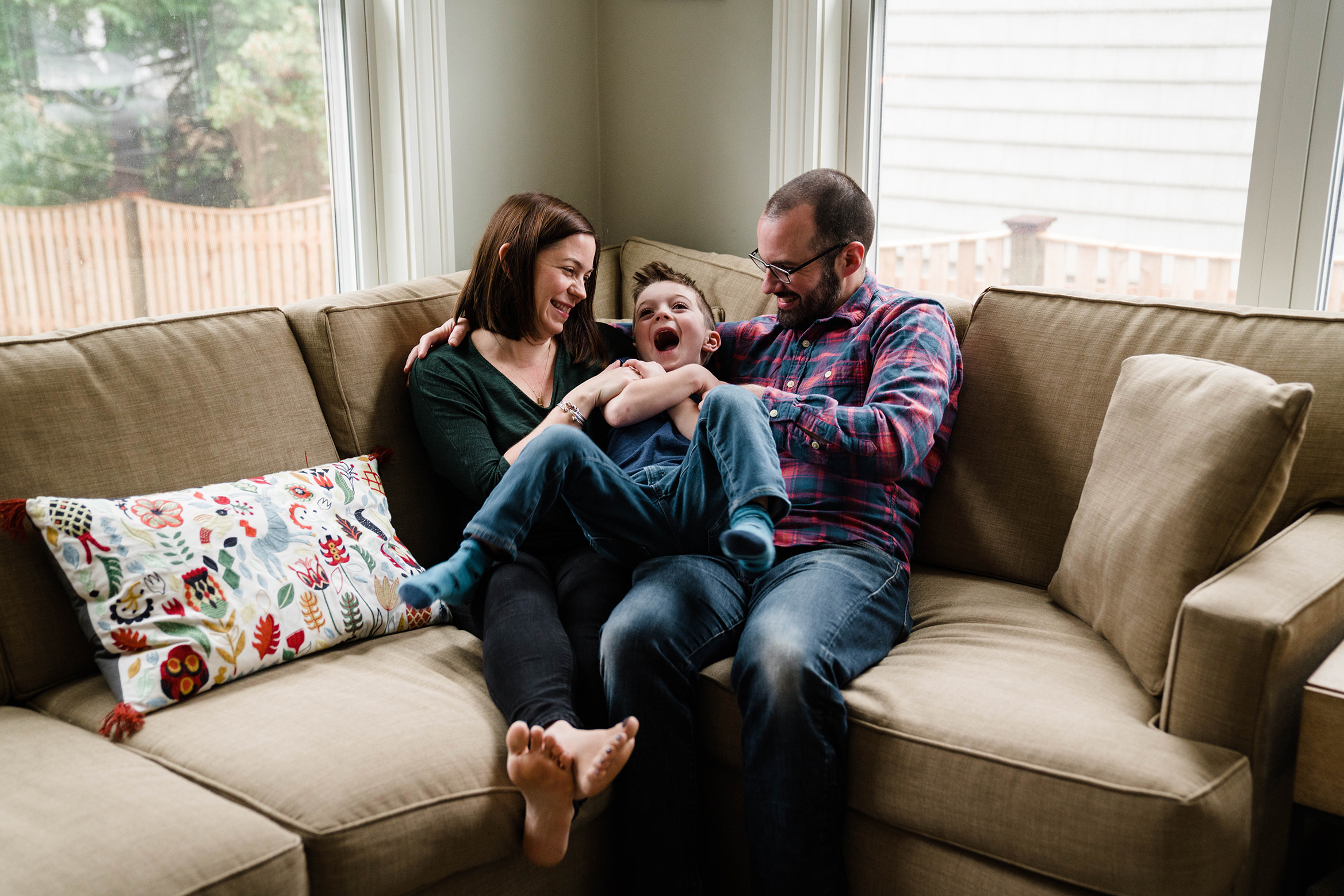 A best of Boston family photograph of a family cuddling and laughing on the couch during an in home family session in Boston