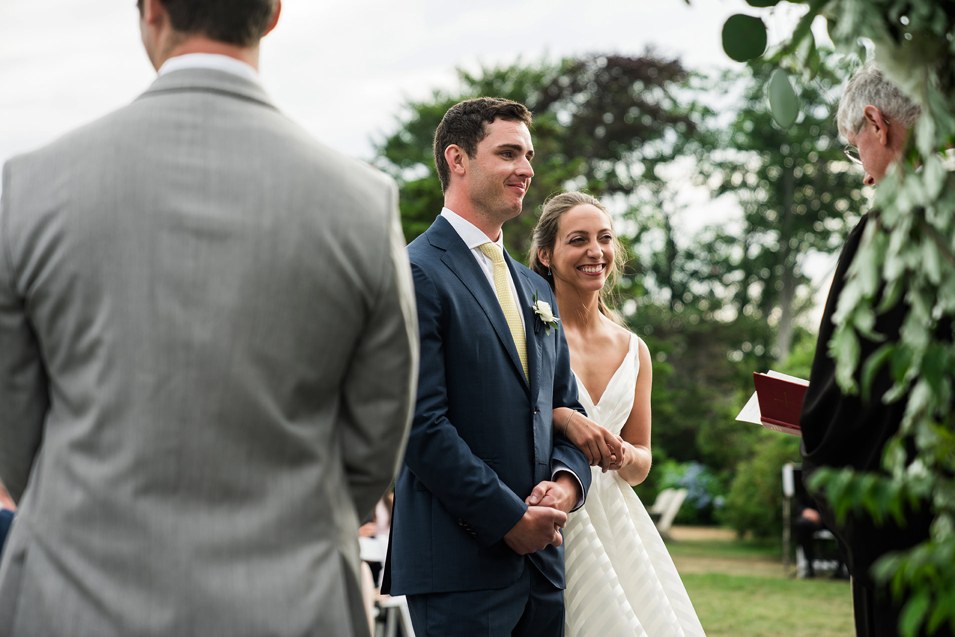 A best of Boston wedding photograph of a couple smiling and embracing during their outdoor wedding ceremony at Castle Hill Inn