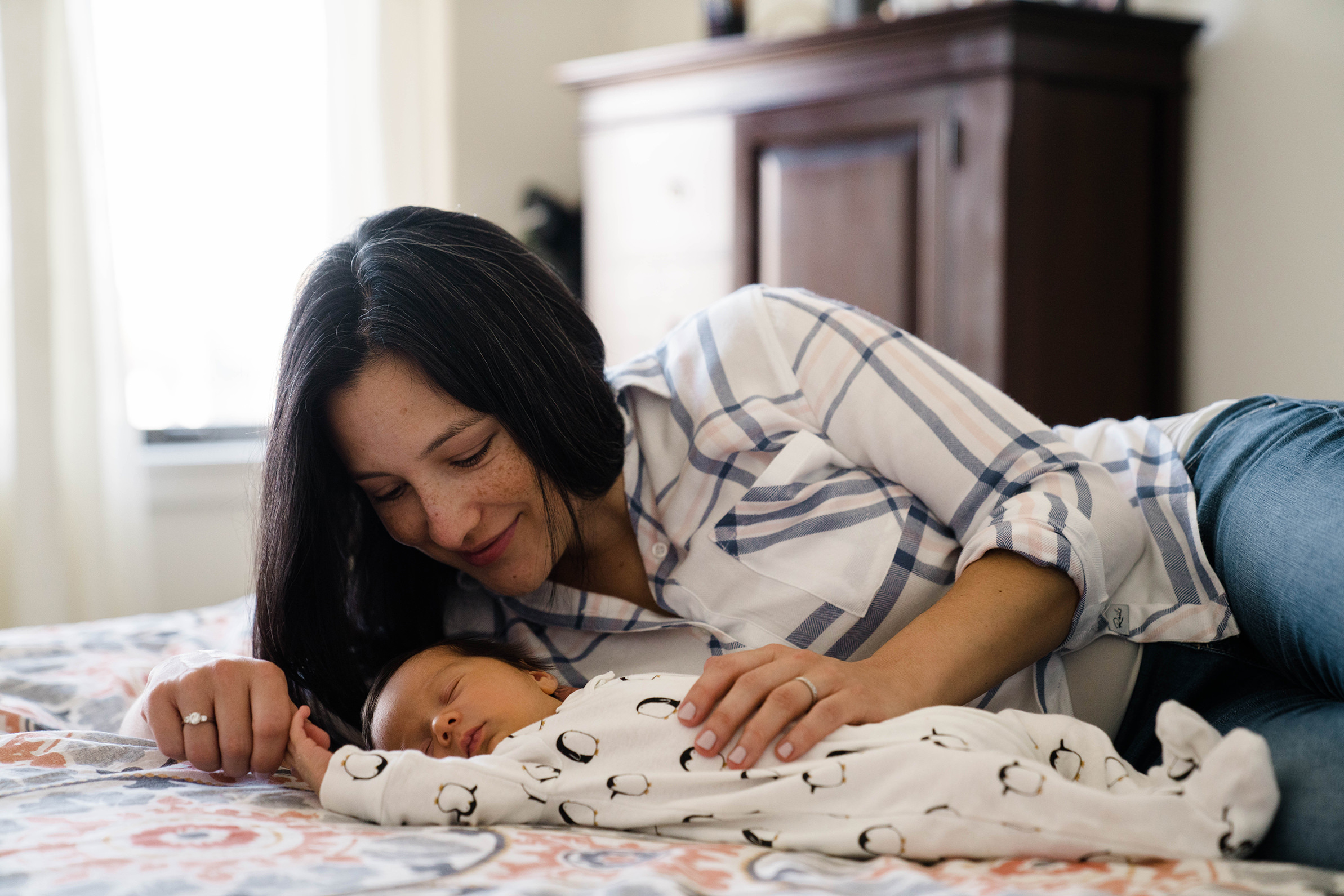 A best of Boston family photograph of a mom cuddling her newborn son as he sleeps during a in home lifestyle newborn session