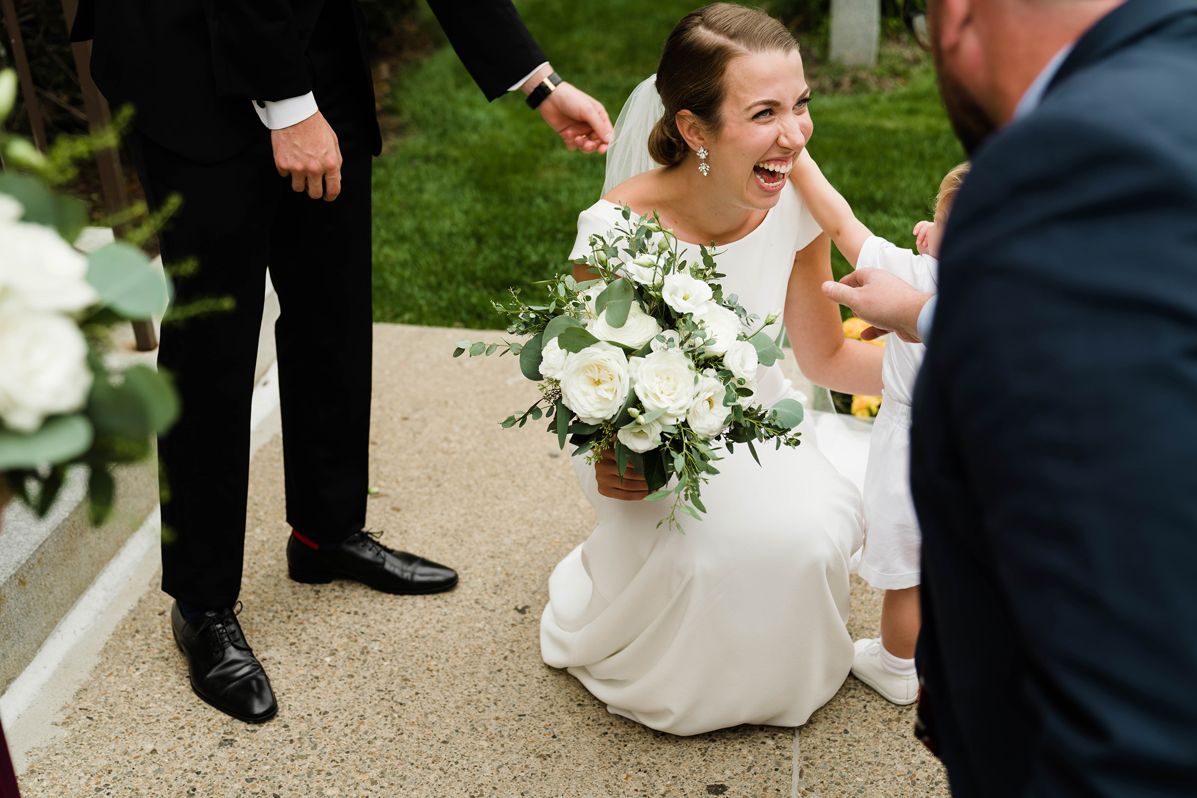 A best of Boston wedding photograph of a bride laughing while the page boy plays with her earrings after their Boston wedding ceremony