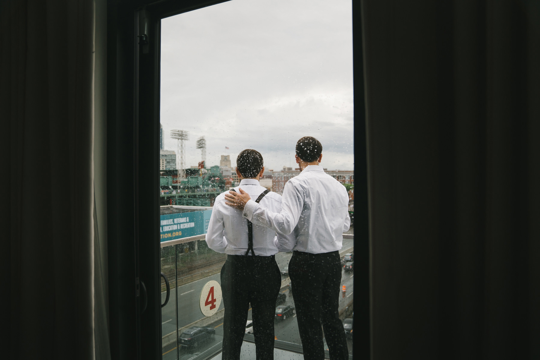 A best of Boston Wedding photograph of two brothers standing outside admiring the view of Fenway Park during their Commonwealth Hotel wedding