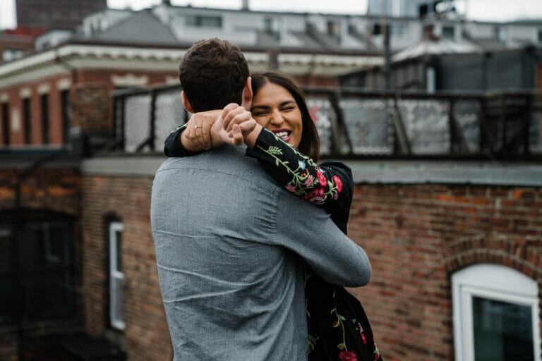 A documentary portrait of a couple hugging on the roof of their Beacon Hill home during their Boston Engagement Session