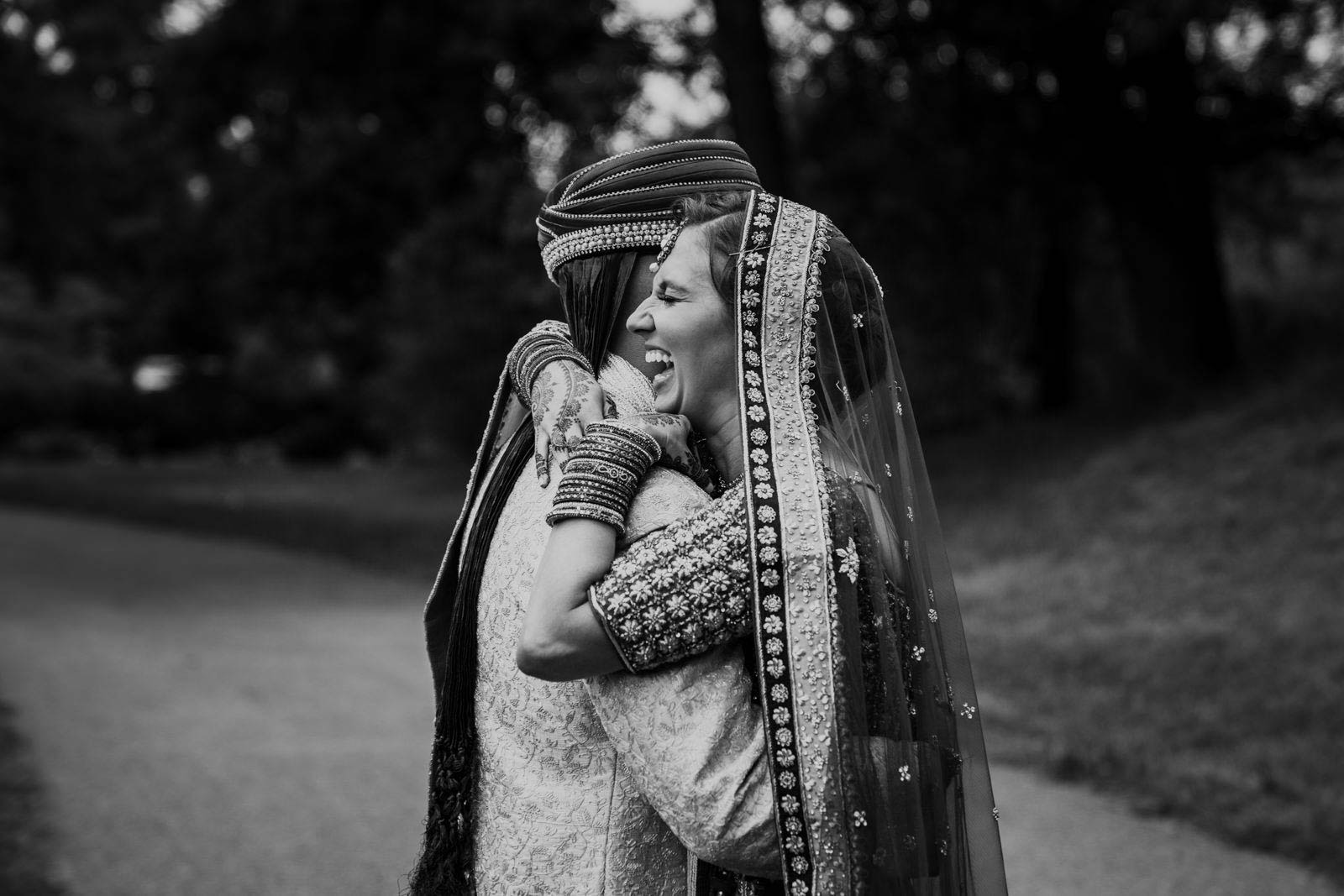 A documentary photograph of a bride and groom hugging each other during the first look at their Indian American wedding in Boston