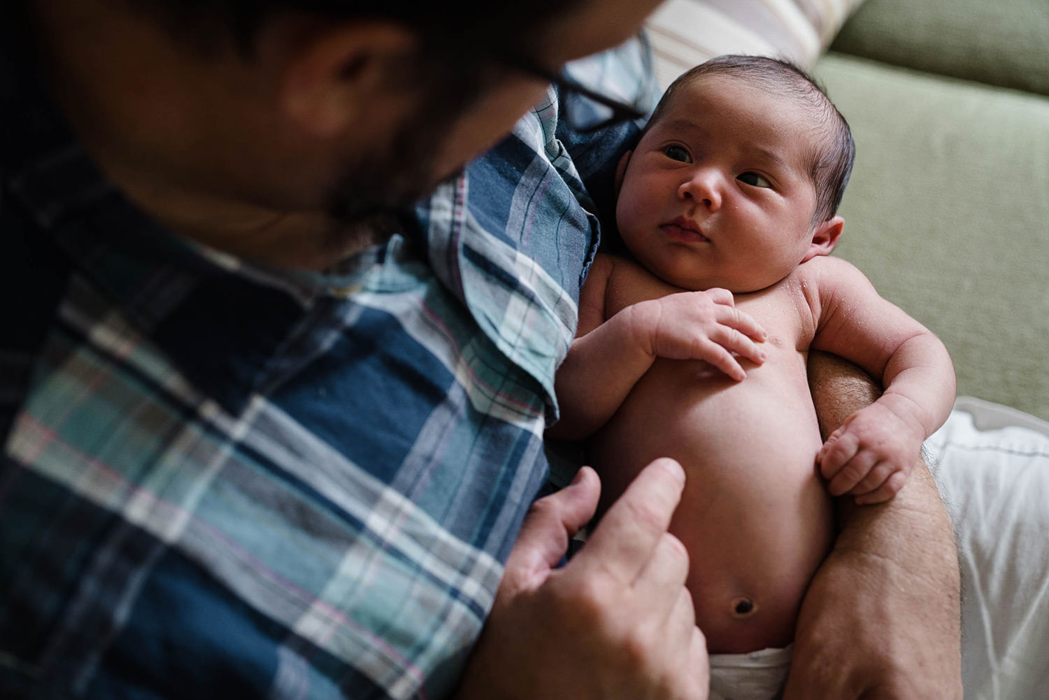 A documentary photograph of a father holding his newborn daughter during an in home documentary newborn session in Boston's Jamaica Plain
