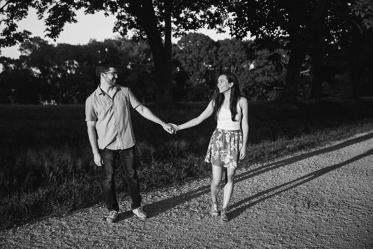 A documentary photograph of a couple holding hands during their world's end engagement session outside of Boston