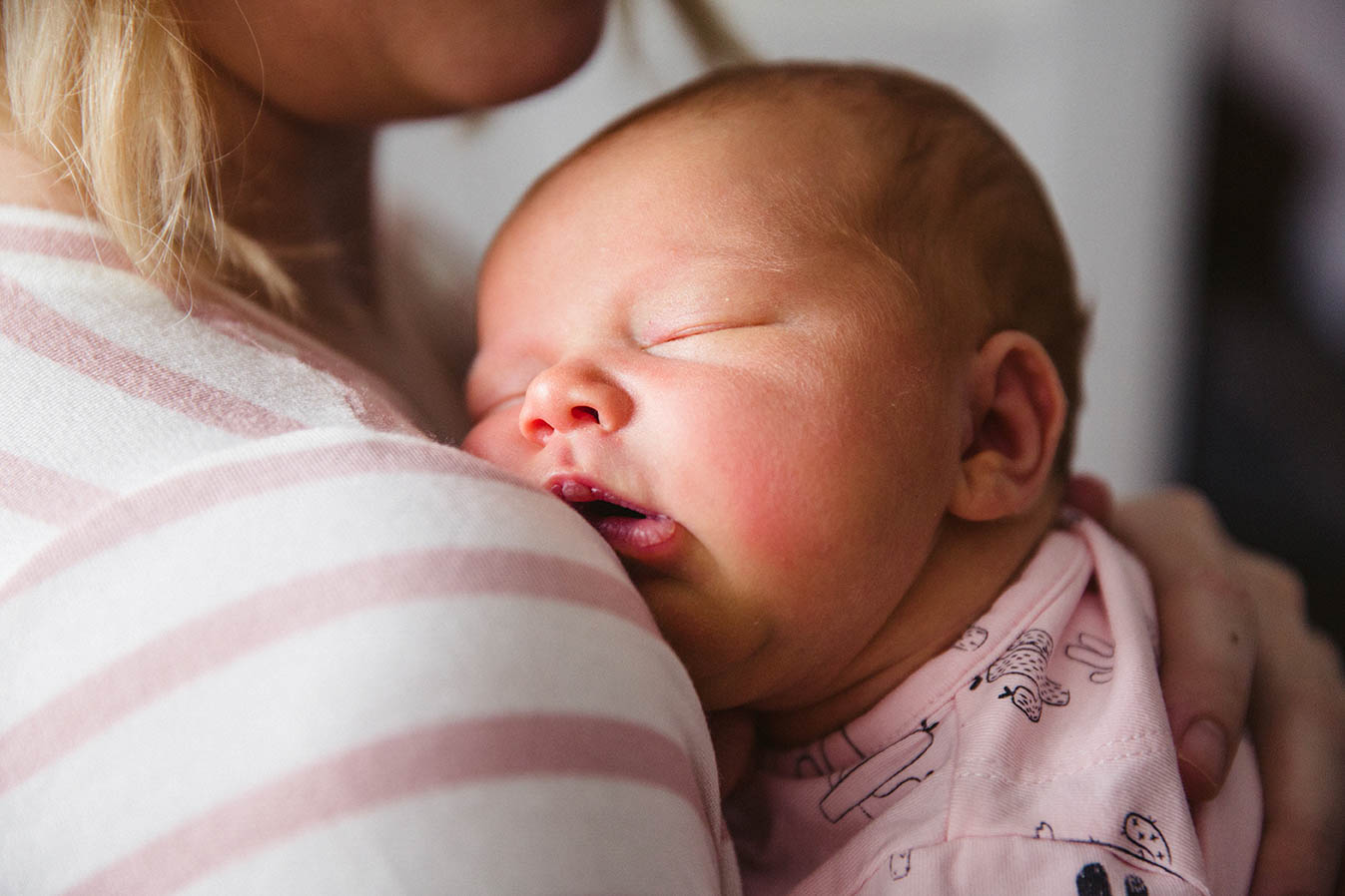 A documentary photograph of a newborn baby sleeping on her mom during an in home newborn session in Boston