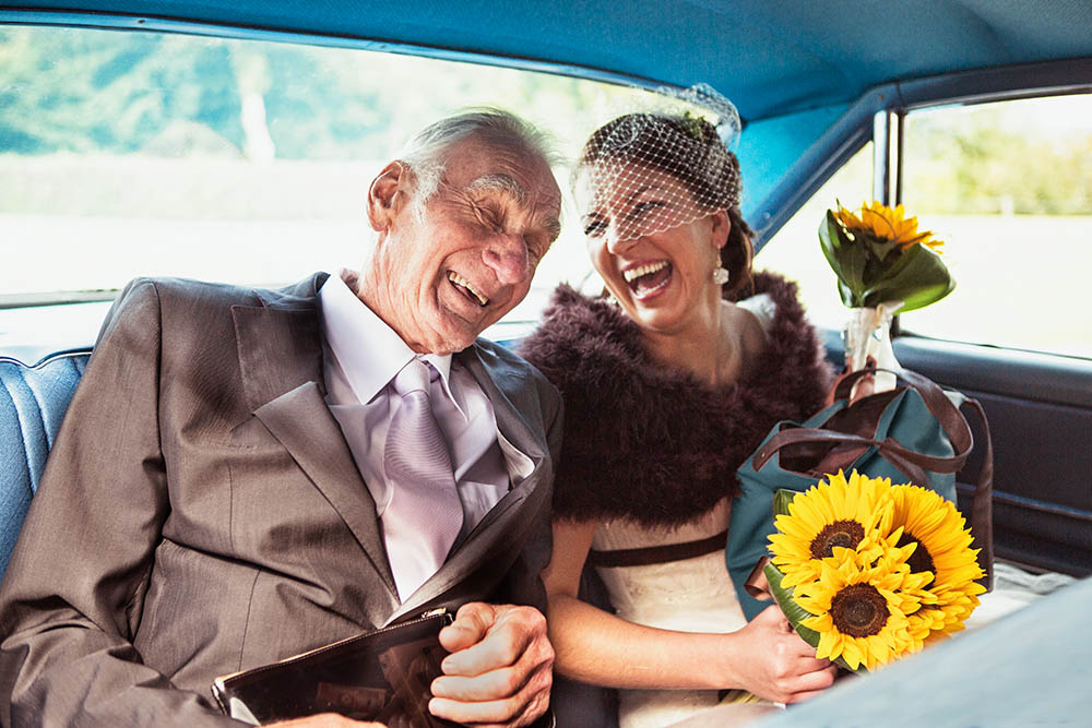 A documentary photograph of a bride laughing with her grandfather on the way to her Boston wedding