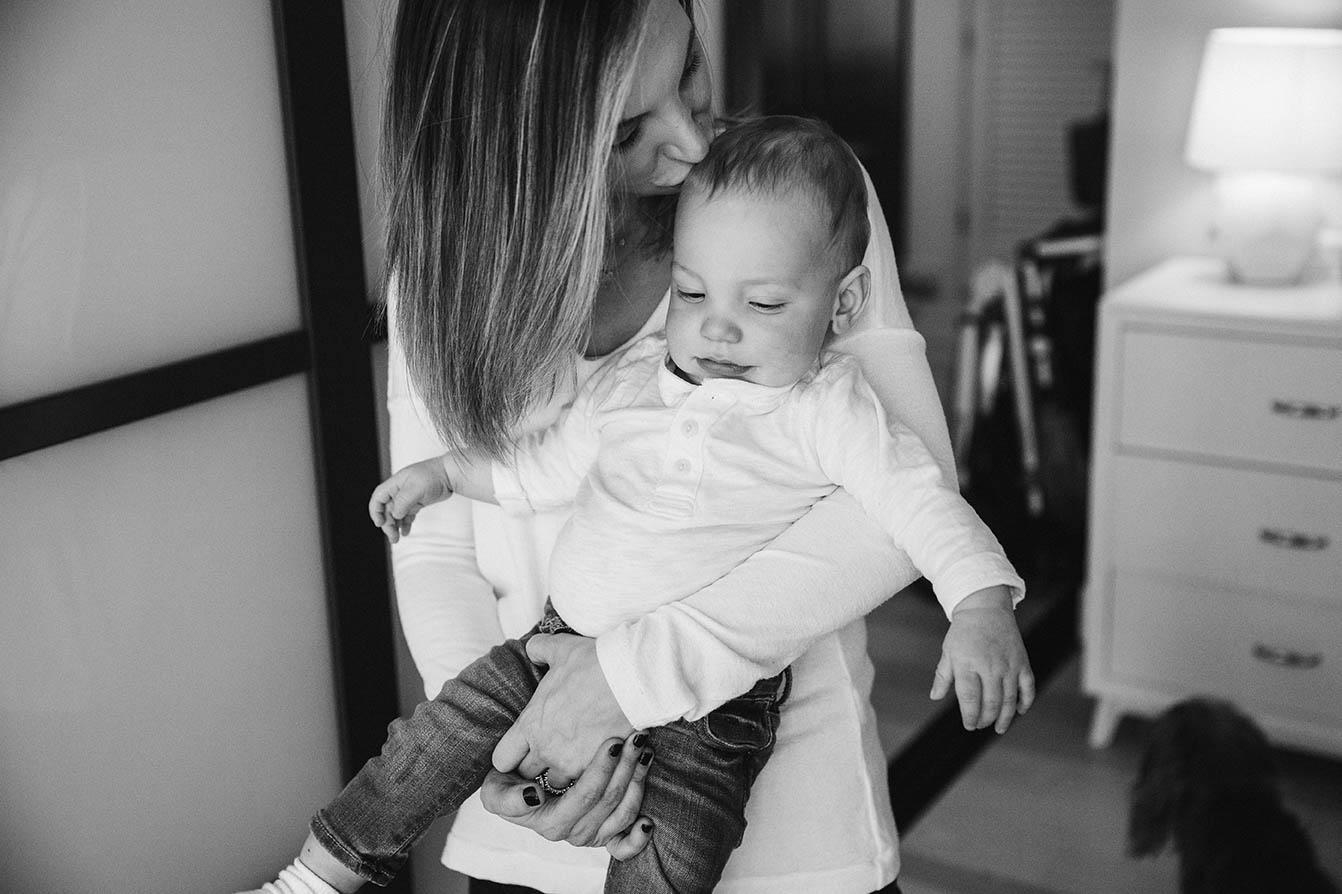A documentary photograph of a mom kissing her baby boy during an in home family in Boston