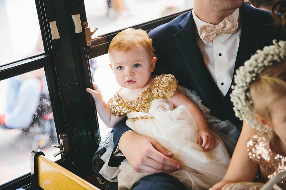 A documentary photograph of a flower girl riding a trolley during an Boston Wedding