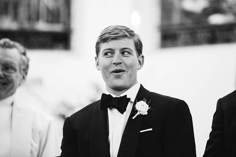 A documentary photograph of a groom's expression as he sees his bride walk up the aisle at their Boston wedding