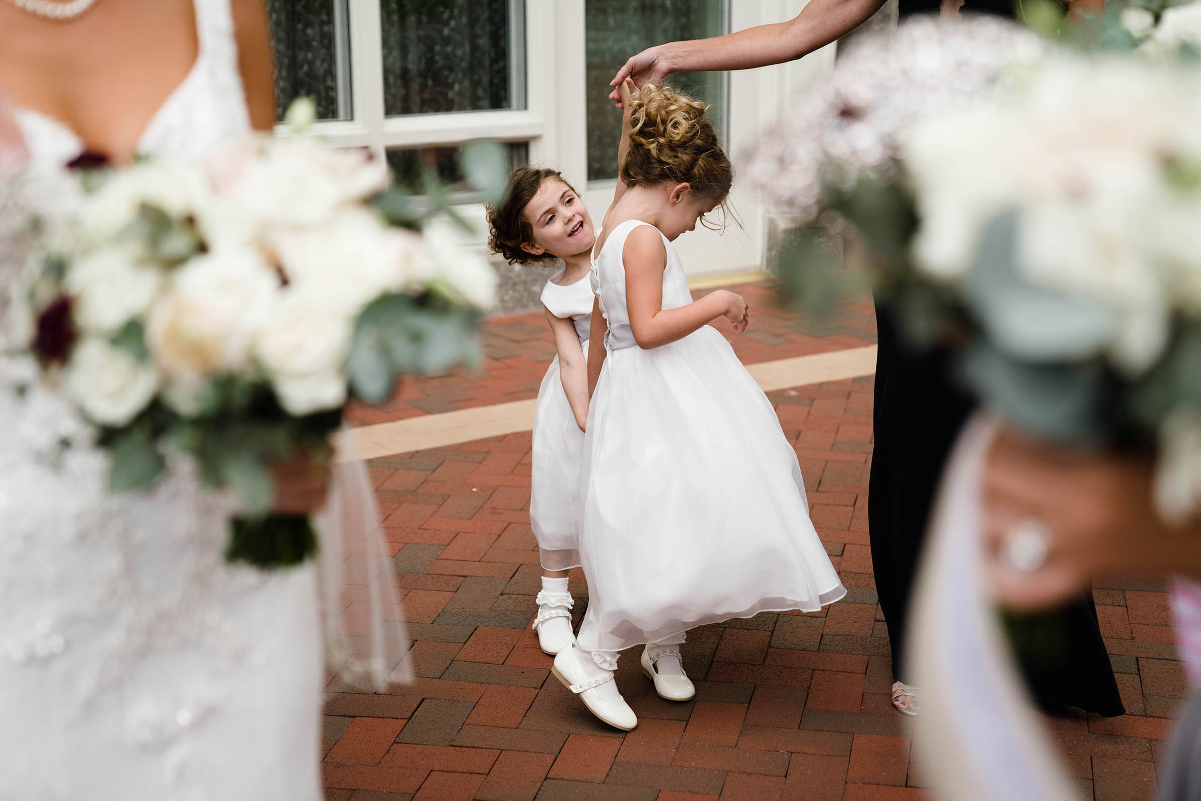 A documentary photograph of two flower girls playing outside the church before a Boston wedding