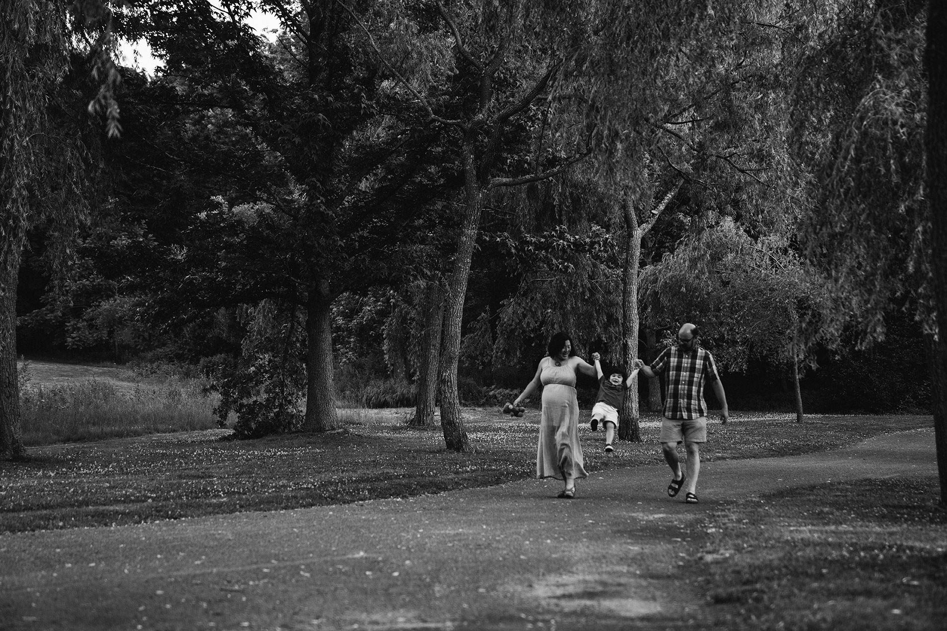 A documentary photograph of a family walking through Larz Anderson park during a maternity family session in Boston