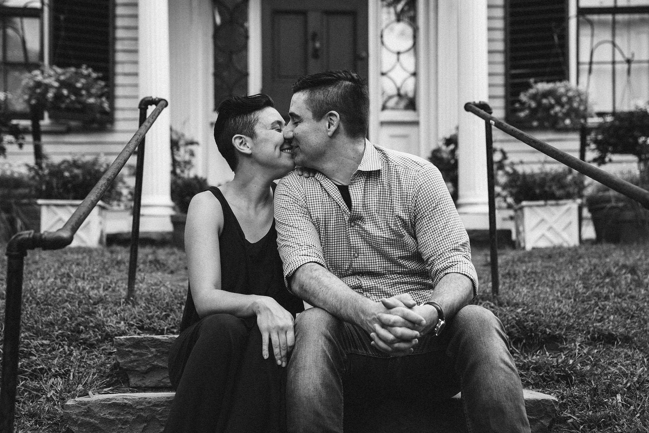 A documentary photograph of parents giving each other a kiss during a Boston family session in Jamaica Plain