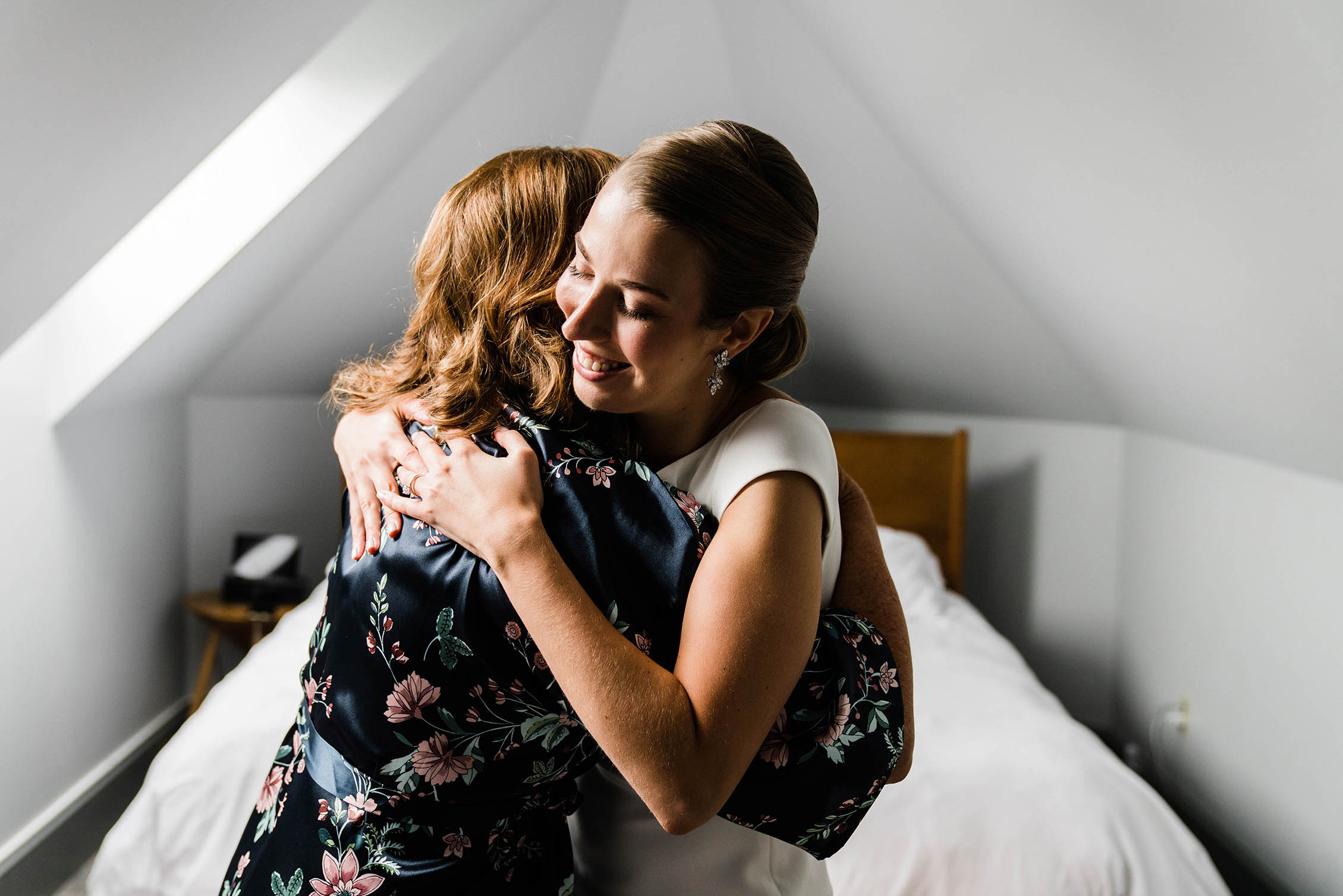A documentary photograph of a bride hugging her mom while she gets ready for her Boston wedding