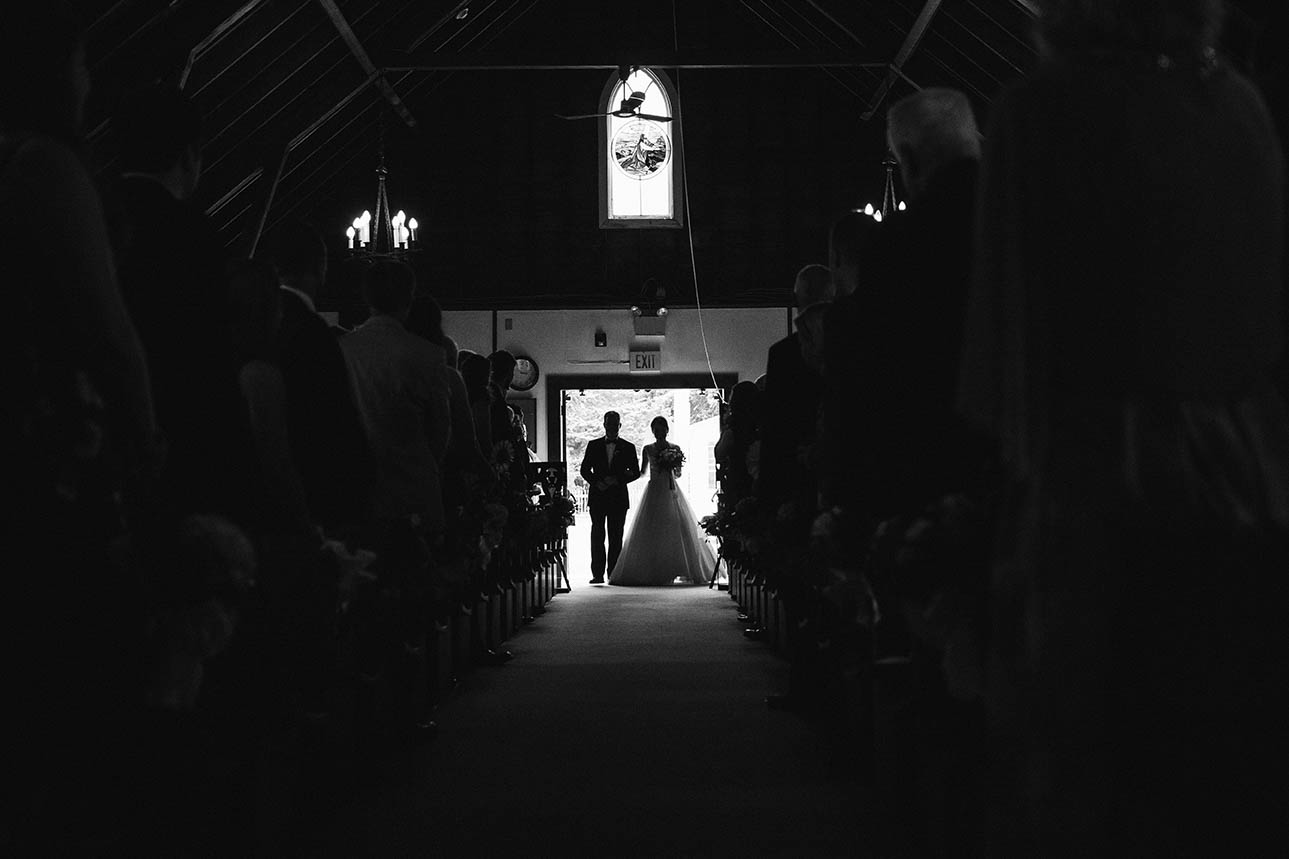 A documentary photograph of a bride entering the church with her father before her Boston wedding ceremony