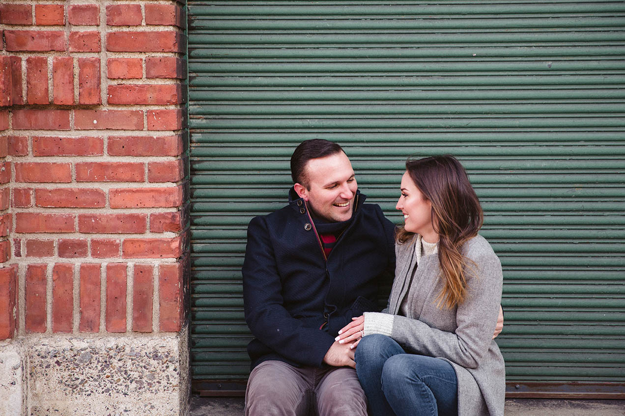 A documentary photograph of a couple talking while they sit together during their Boston engagement session at Fenway Park