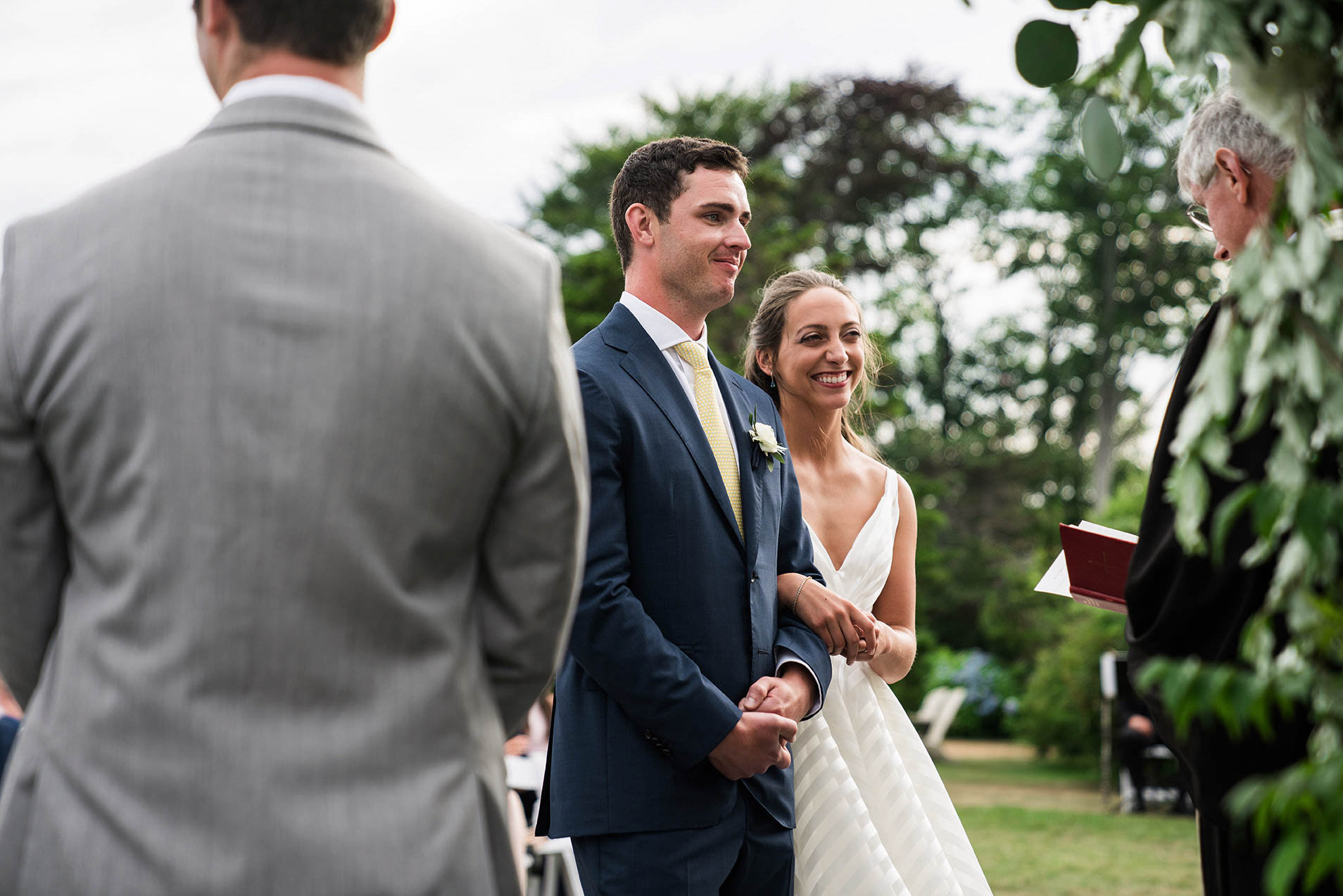 A documentary photograph of a bride and groom smiling during their Castle Hill Inn Wedding ceremony