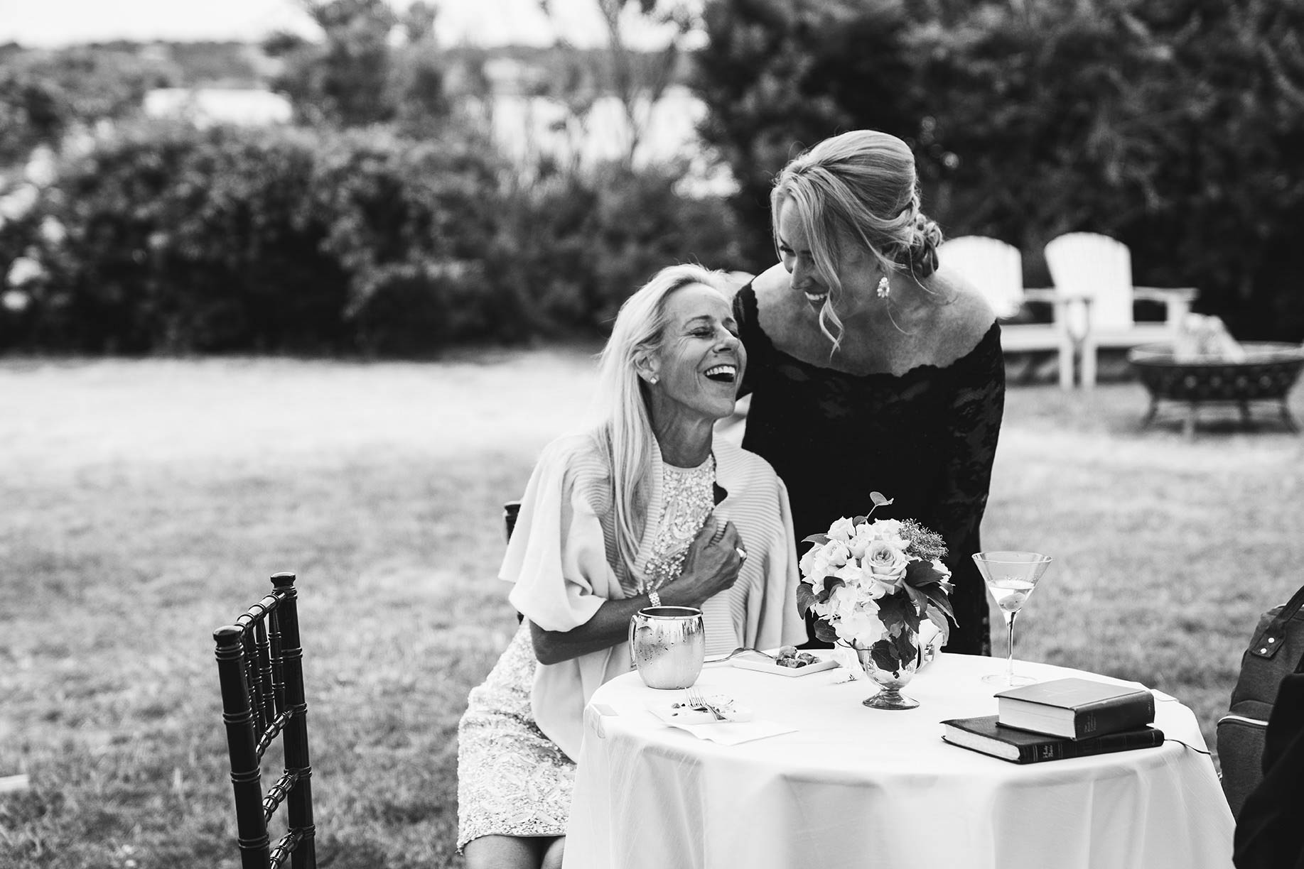 A documentary photograph of guests talking and laughing during an outdoor Boston wedding