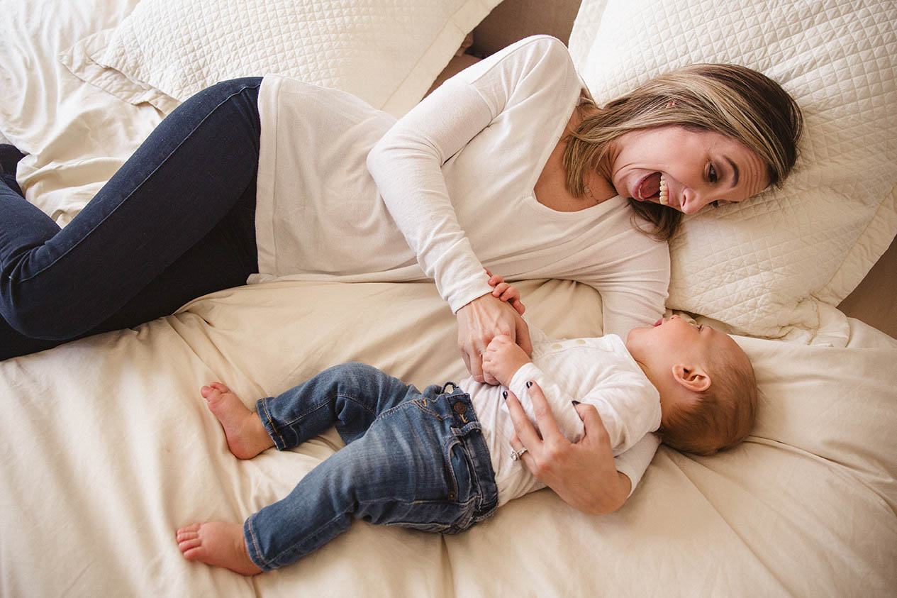 A documentary photograph of a mother and son snuggling in bed during an in home family session in Boston