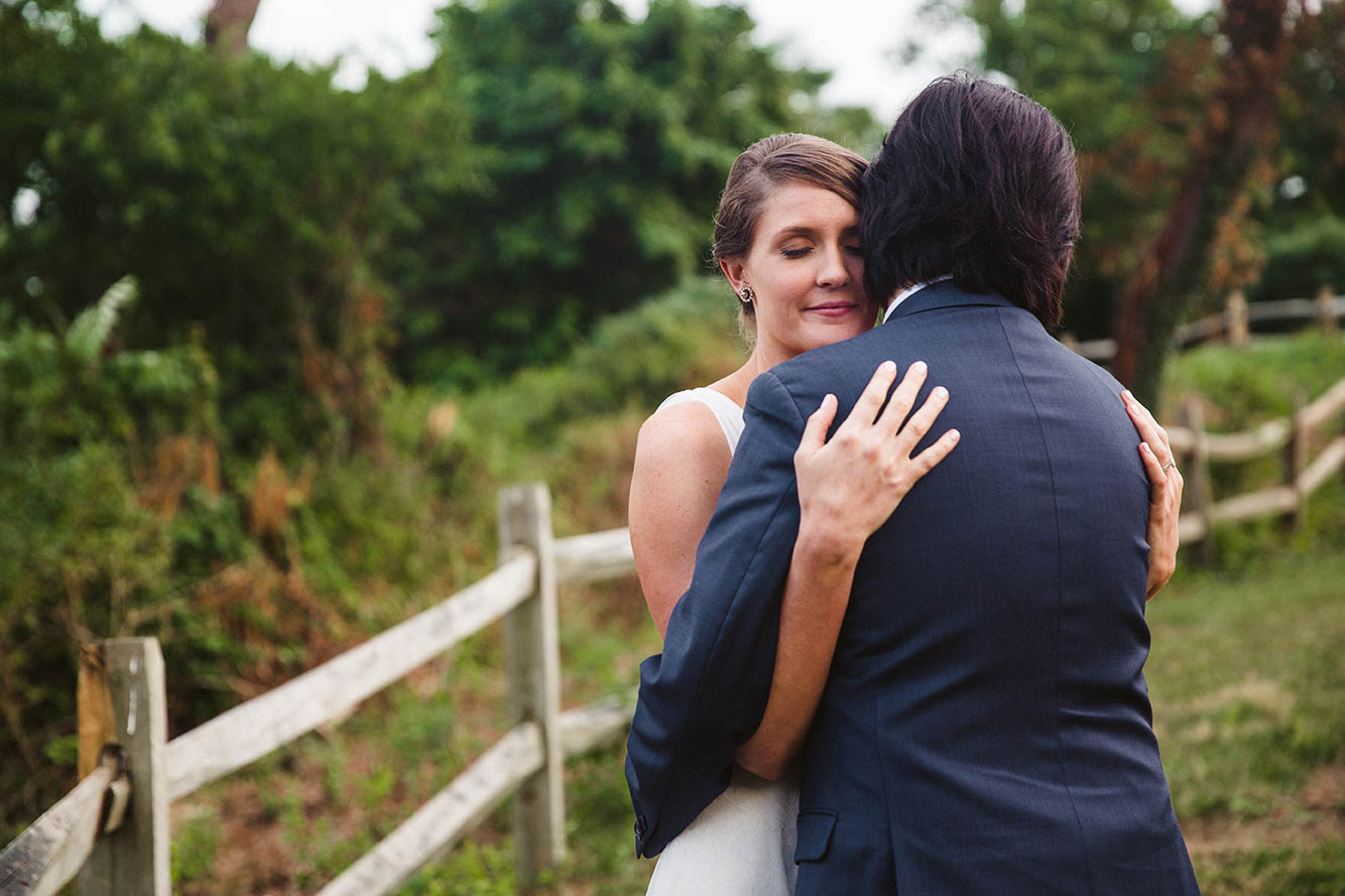 A documentary photograph of a bride and groom hugging after their outdoor ceremony in Boston