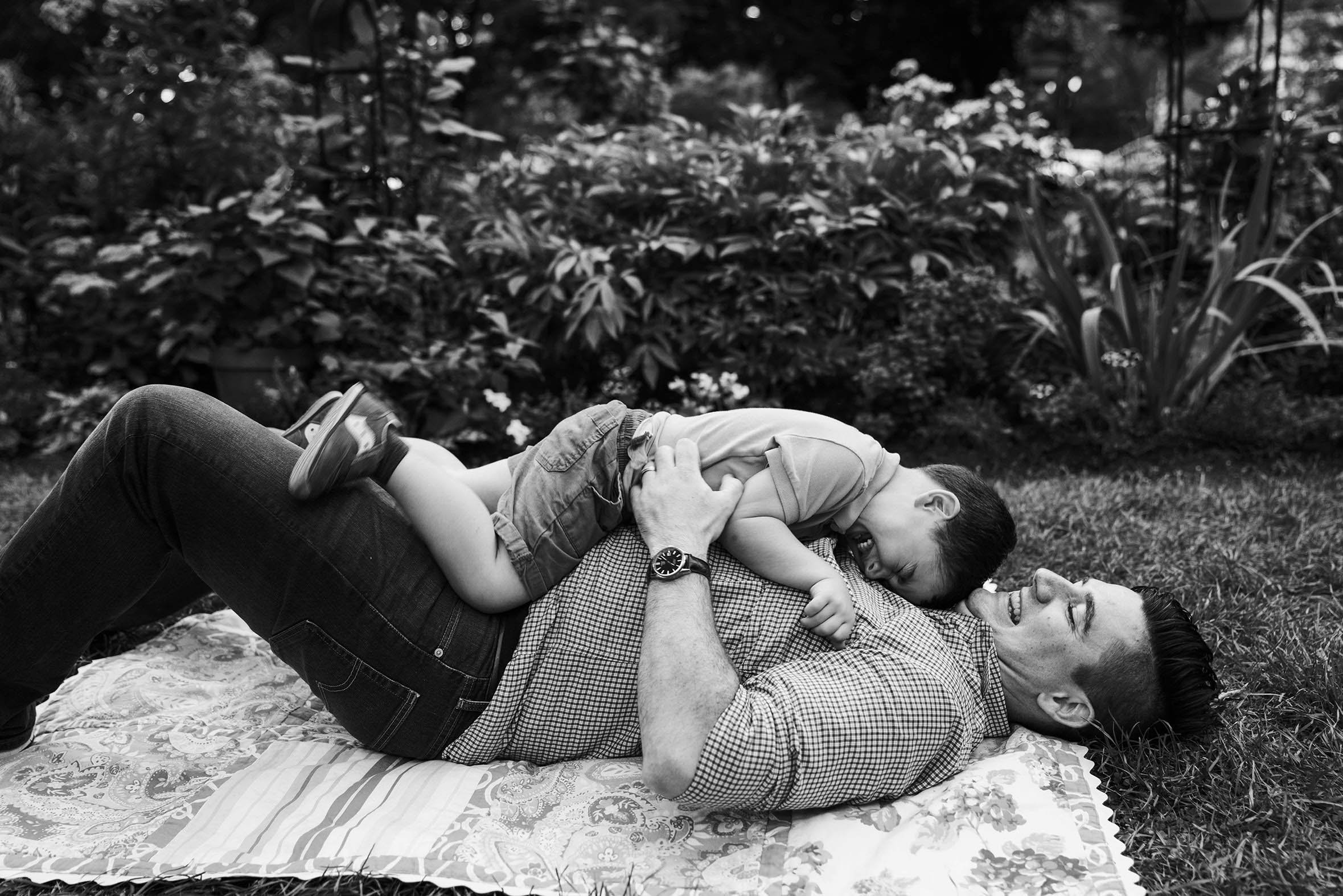 A documentary photograph of a father and son playing and laughing during their Boston family session