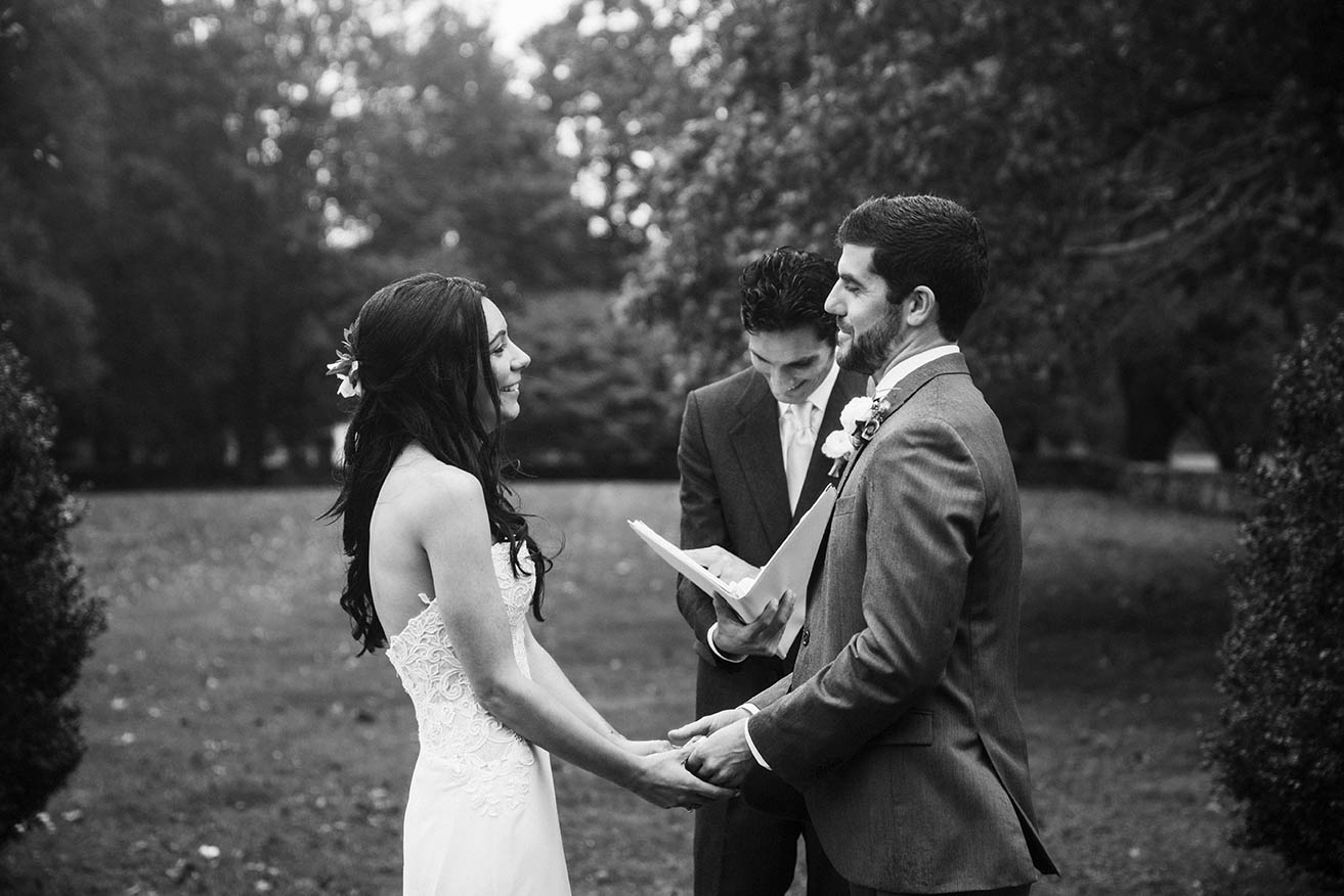 A documentary photograph of a bride and groom saying their vows during their outdoor wedding ceremony in the rain at mount hope farm