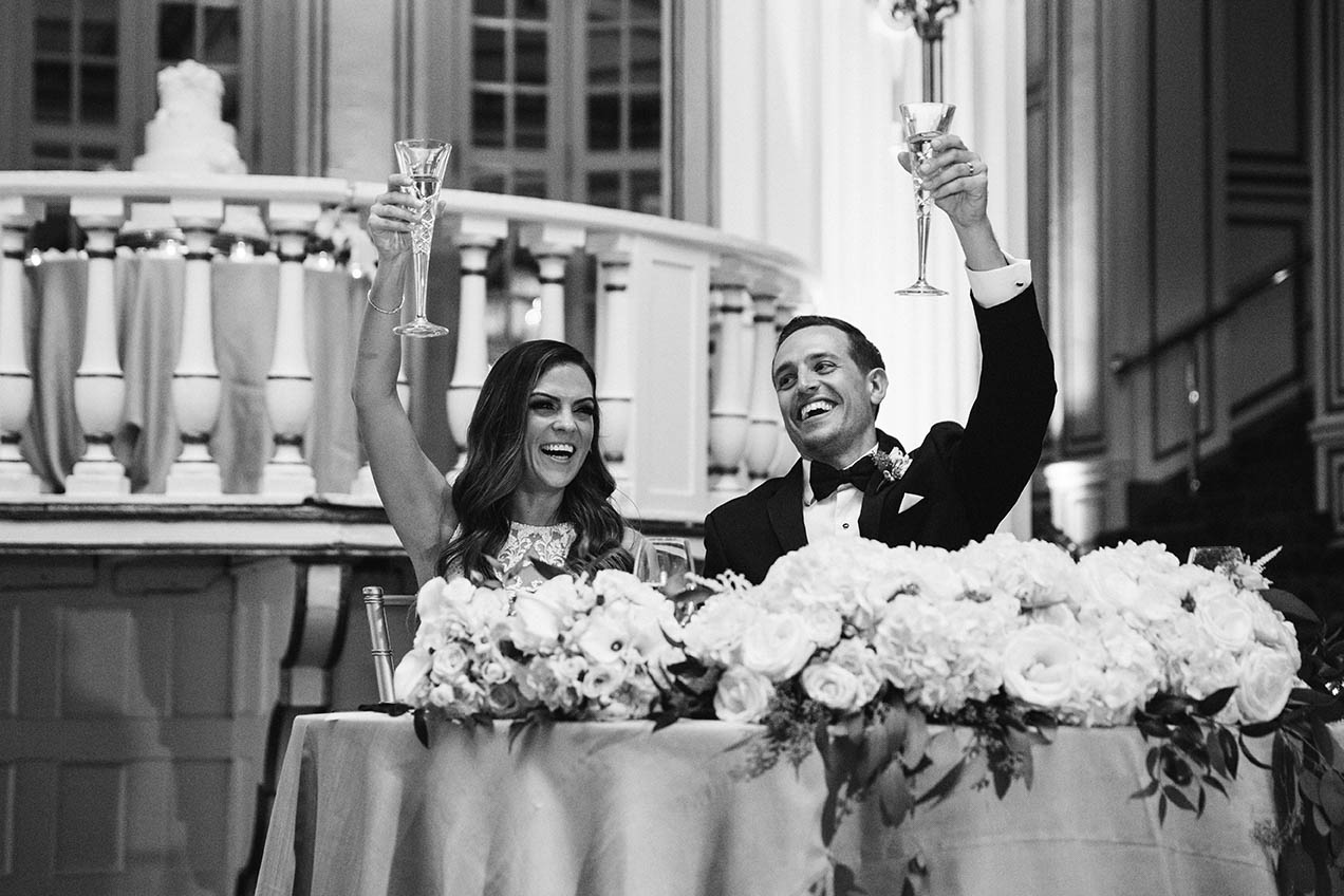 A documentary photograph of a bride and groom raising their glasses during the wedding speeches at their Fairmont Copley Boston Wedding