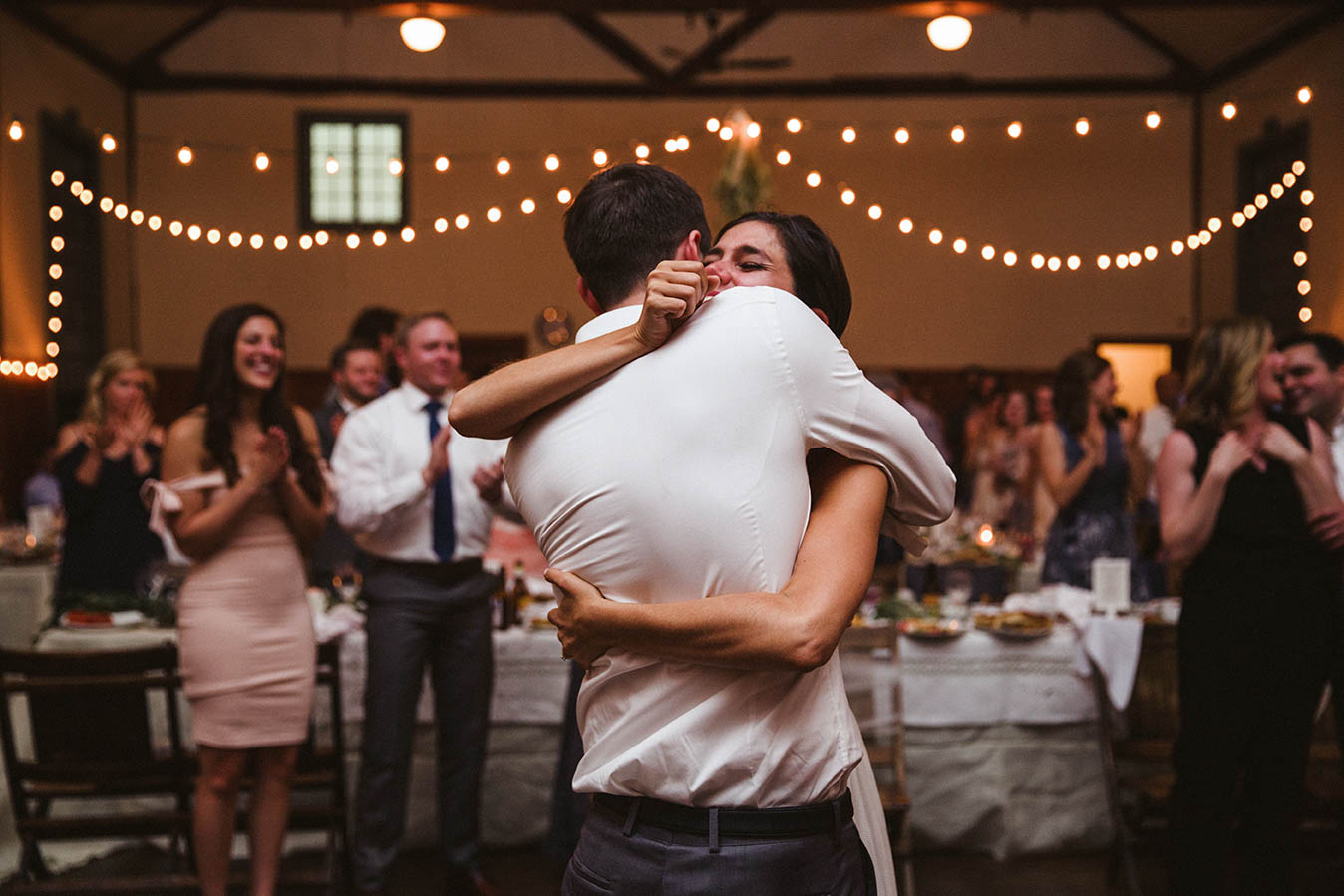 A documentary photograph of a bride hugging her brother after he sang a song during their Boston Wedding reception