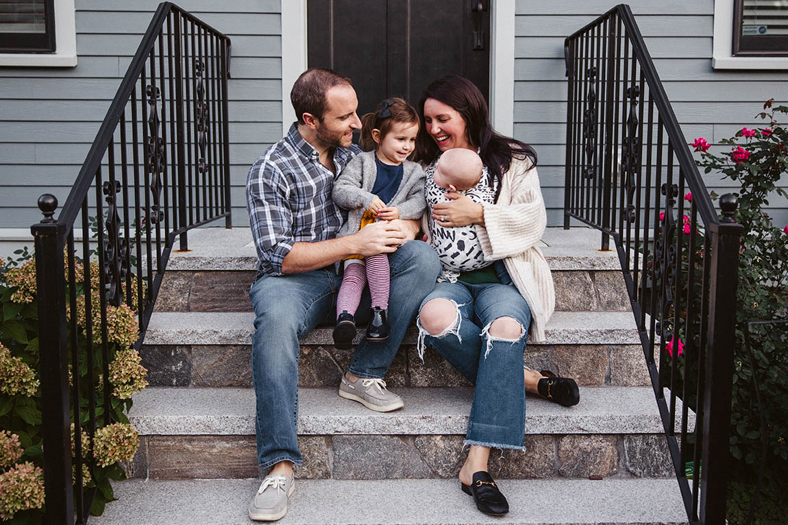A documentary portrait of a family sitting on their front steps during an in home family session in Boston's Jamaica Plain