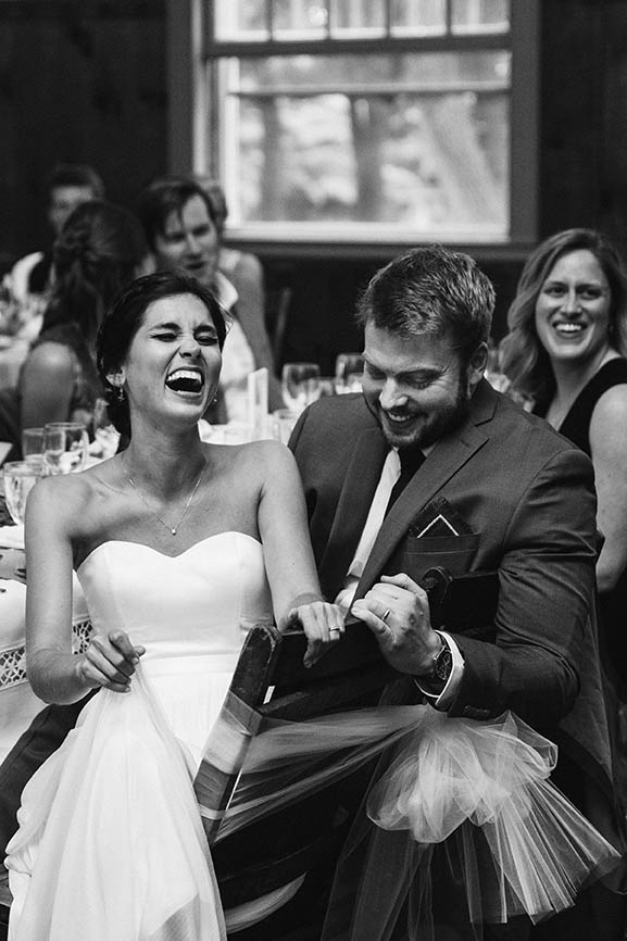 A documentary photograph of a bride and groom laughing during the wedding speeches at their Boston wedding