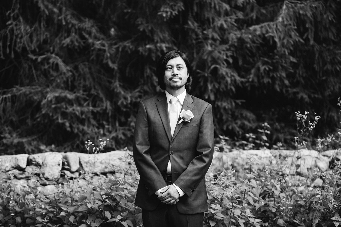A documentary photograph of a groom waiting for his bride to walk down the aisle during a outdoor wedding ceremony at plimouth plantation outside of Boston