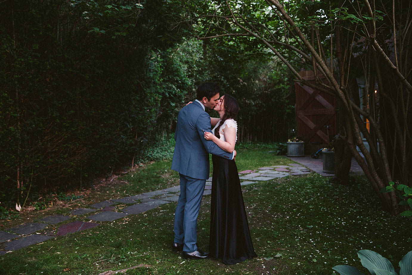 A documentary photograph of a bride and groom sharing a kiss during the end of their in home wedding on the cape