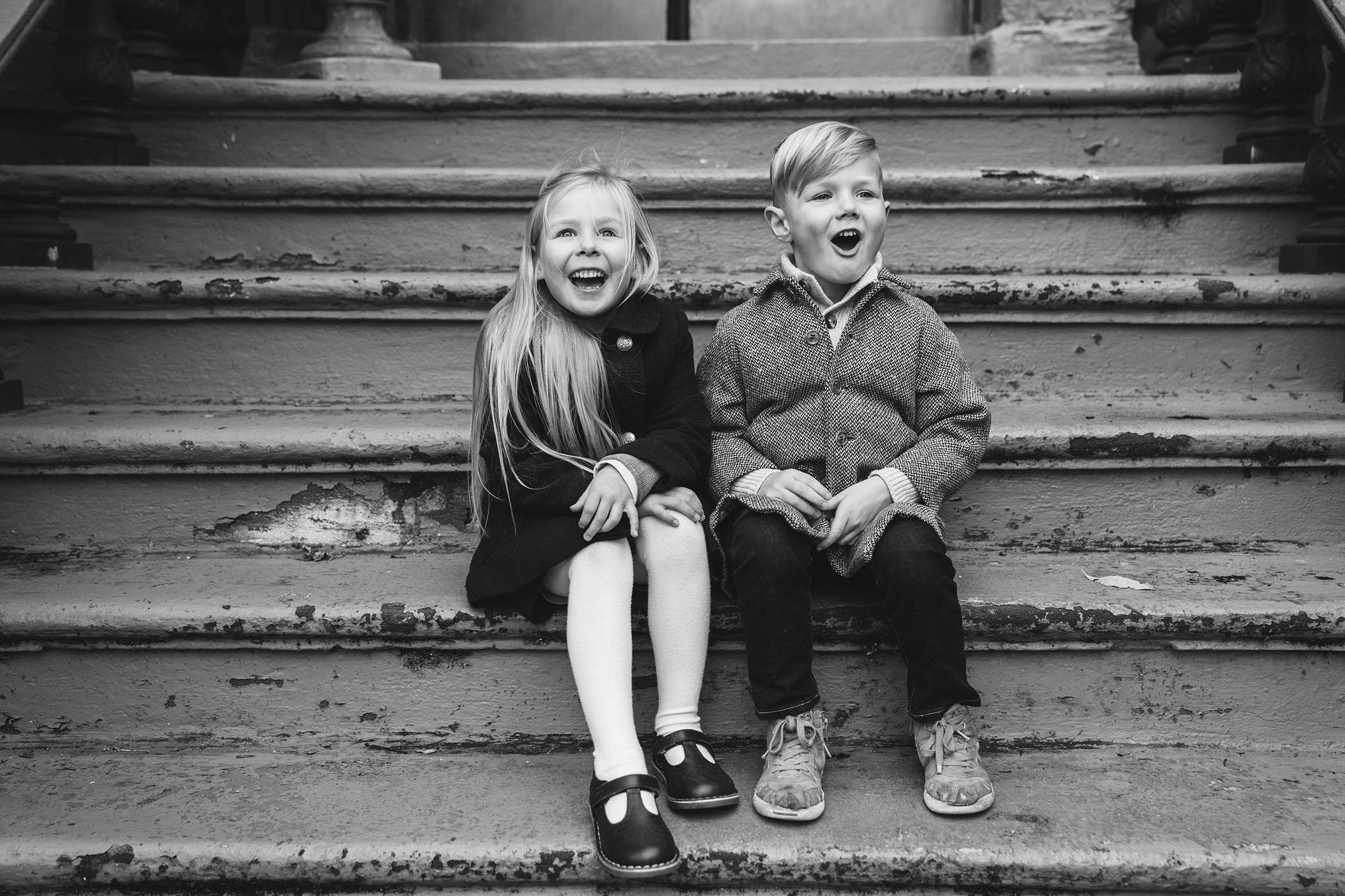 A documentary photograph of two kids being silly on their front steps during an in home family session in Boston's South End