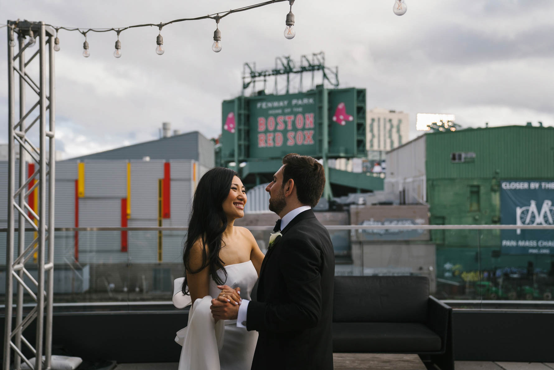 A documentary portrait of a couple dancing on the roof of commonwealth hotel with Fenway Park in the background of their Boston Wedding