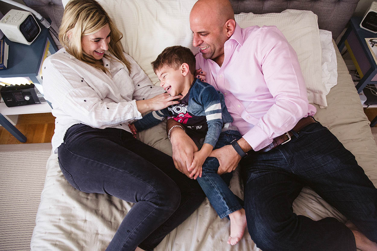 A documentary photograph of a family snuggling and playing in bed during their in home family session in Boston