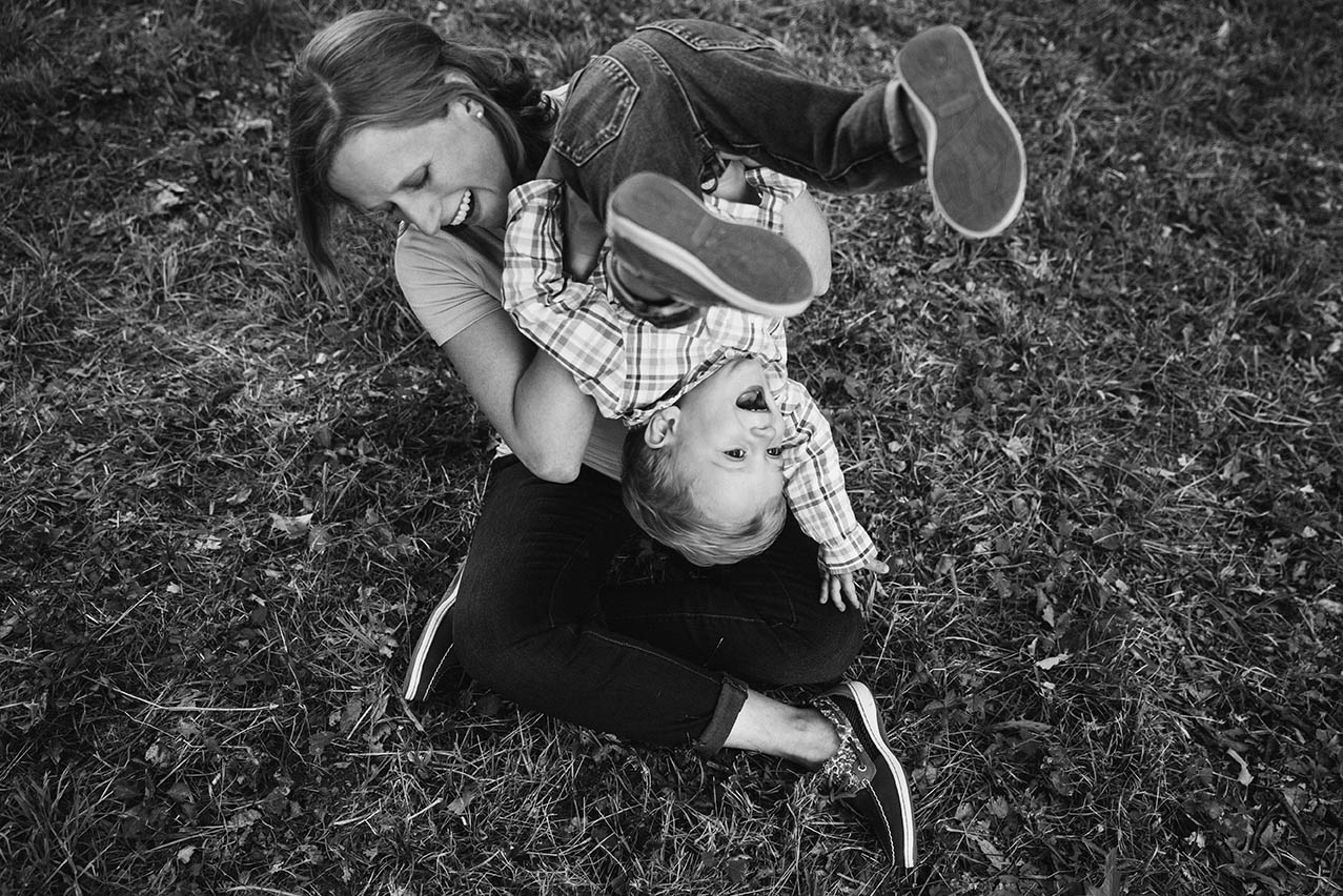 A documentary photograph of a mom playing with her son during their family session at the Arnold Arboretum in Boston