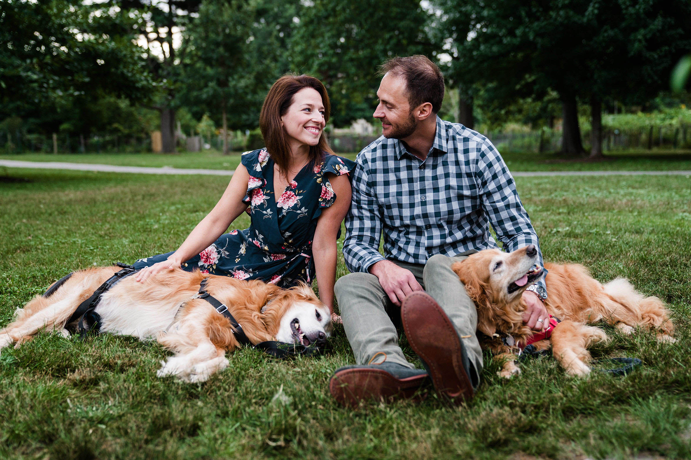 A documentary portrait of a couple hanging out with their dogs at Back Bay Fens during their Boston engagement session