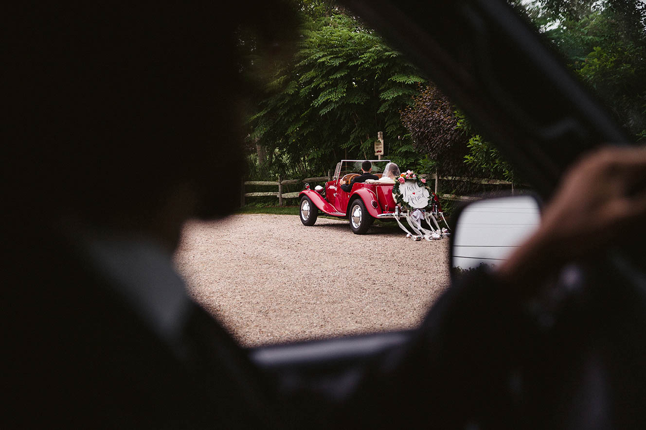 A documentary photograph of a couple driving away in their wedding car during a Boston wedding