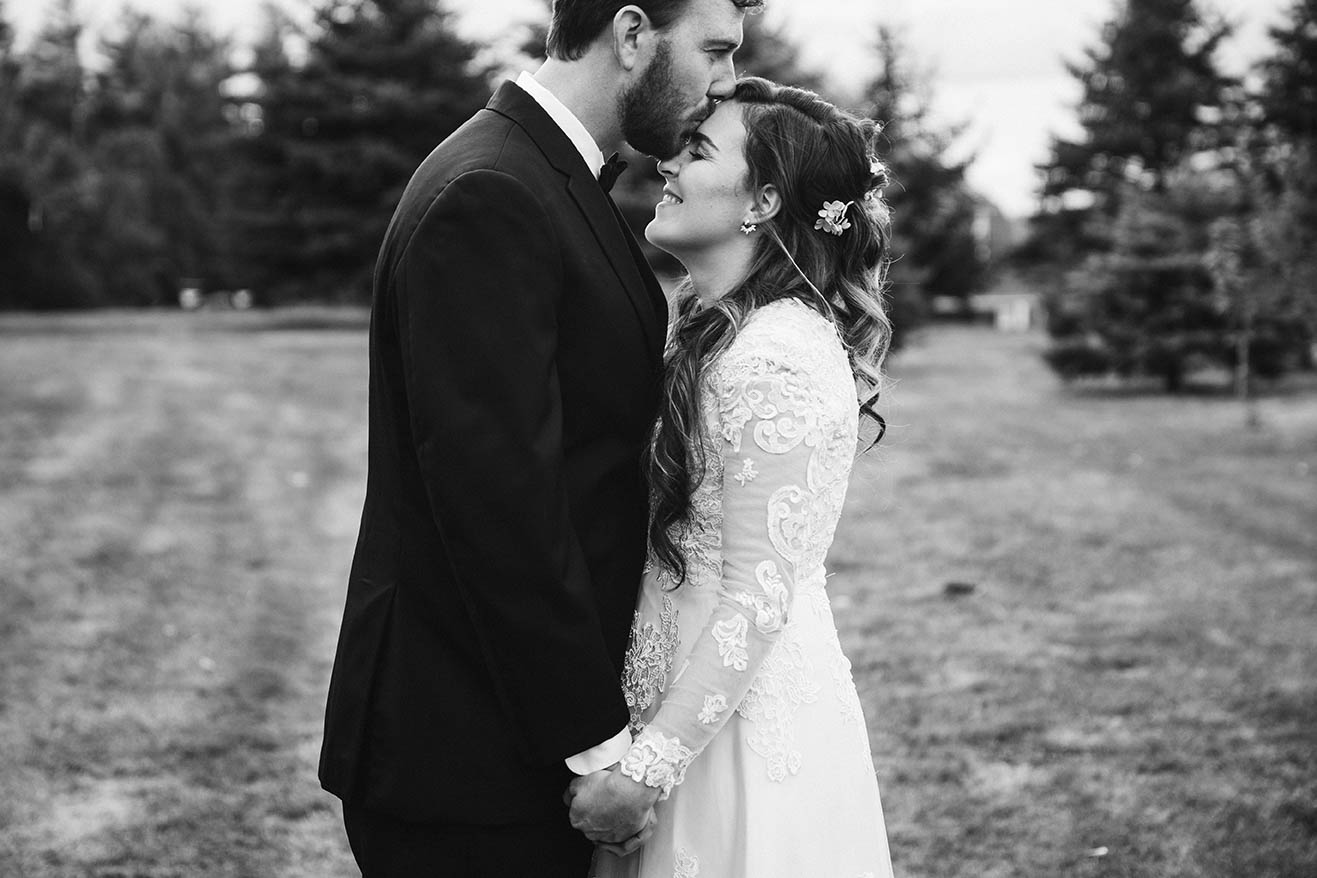 A documentary portrait of a couple embracing after their outdoor wedding ceremony at home in New Hampshire