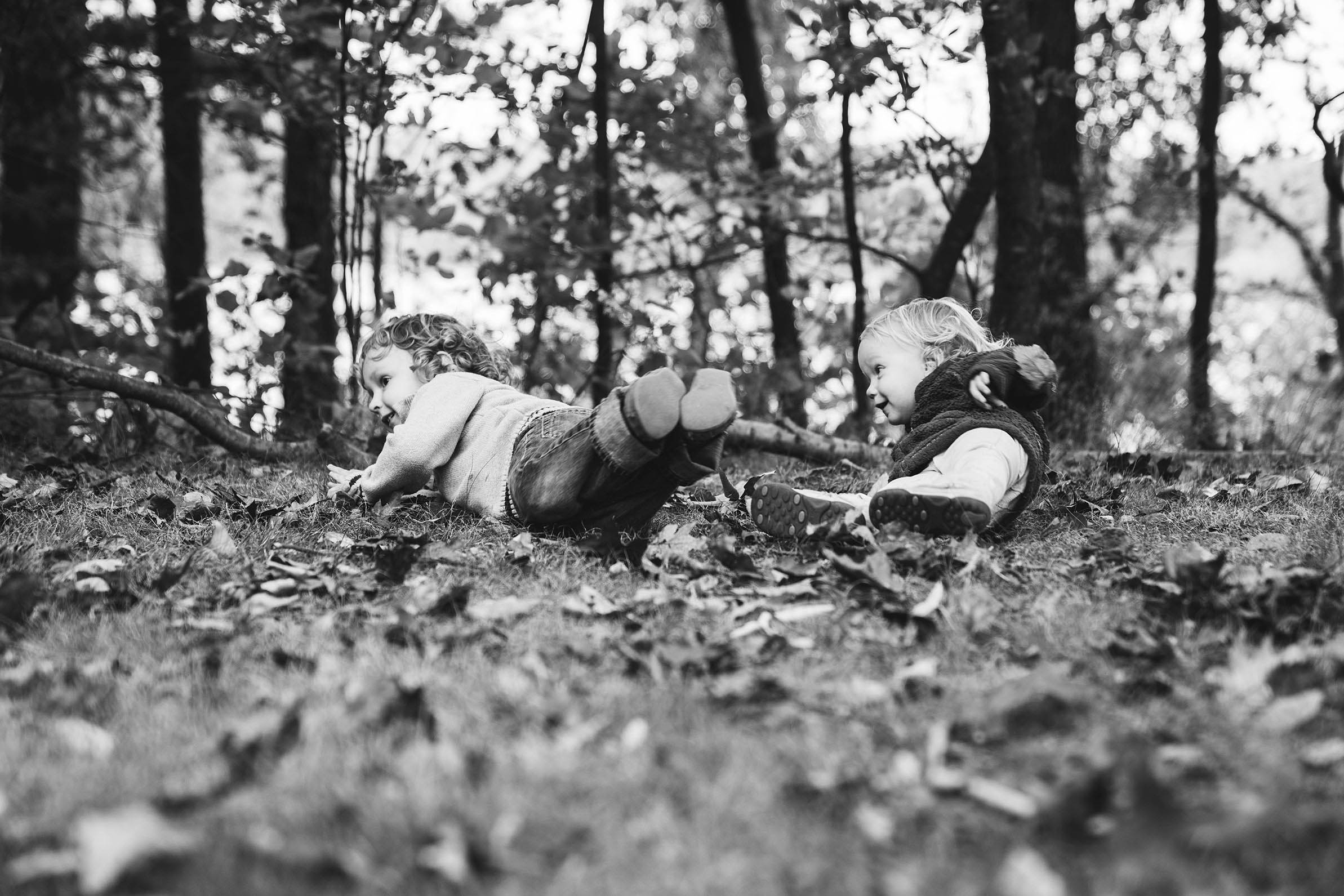 A documentary photograph of two kids rolling in the leave during their family session at the Arnold Arboretum in Boston