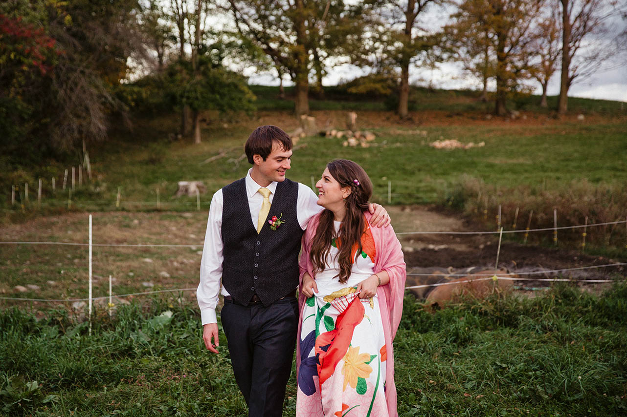 A documentary portrait of a couple walking through a farm during their wedding outside of Boston