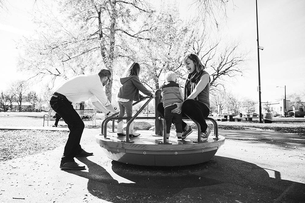 A documentary photograph of a family playing on the merry go round during their family session in Boston