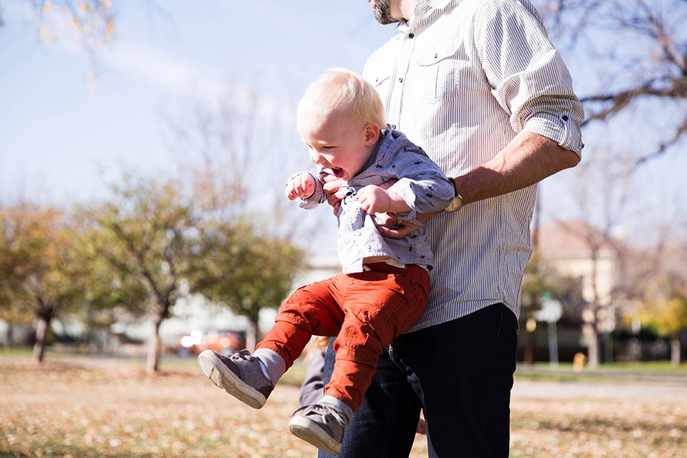 A documentary photograph of a dad playing with his son during a family session in Boston