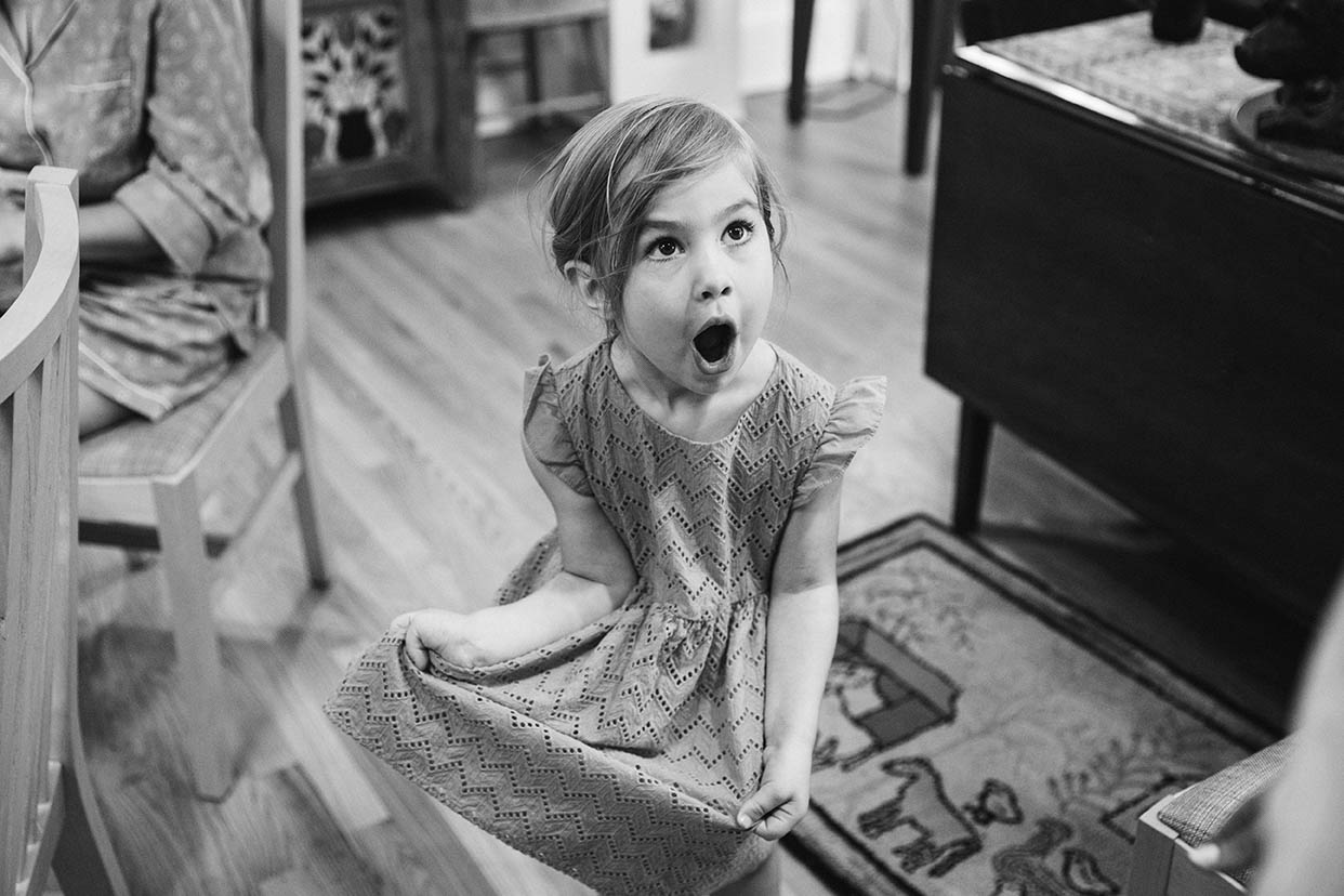 A documentary photograph of a flower girl looking excited before a Moody Mountain Farm wedding in New Hampshire